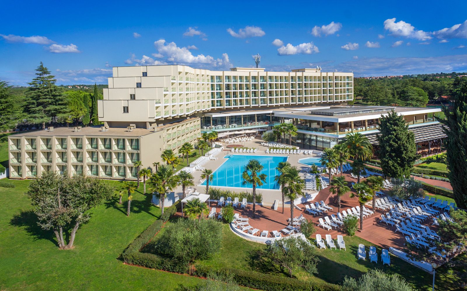 Ein modernes Hotel mit Pool, umgeben von Palmengärten und einer klaren blauen Himmel. Entspannung pur!