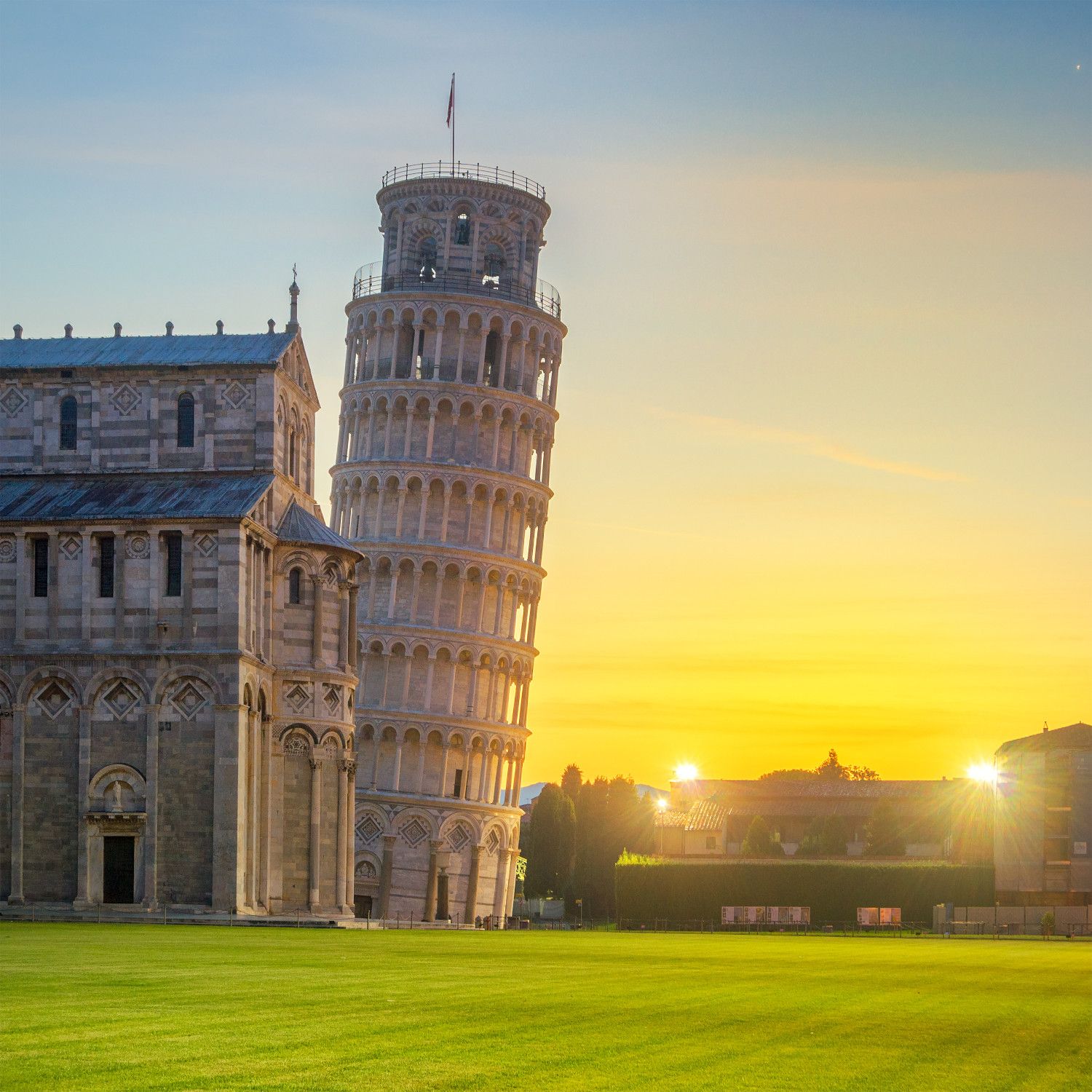 Der schiefe Turm von Pisa steht majestätisch gegen den Sonnenuntergang, neben einer historischen Kirche.