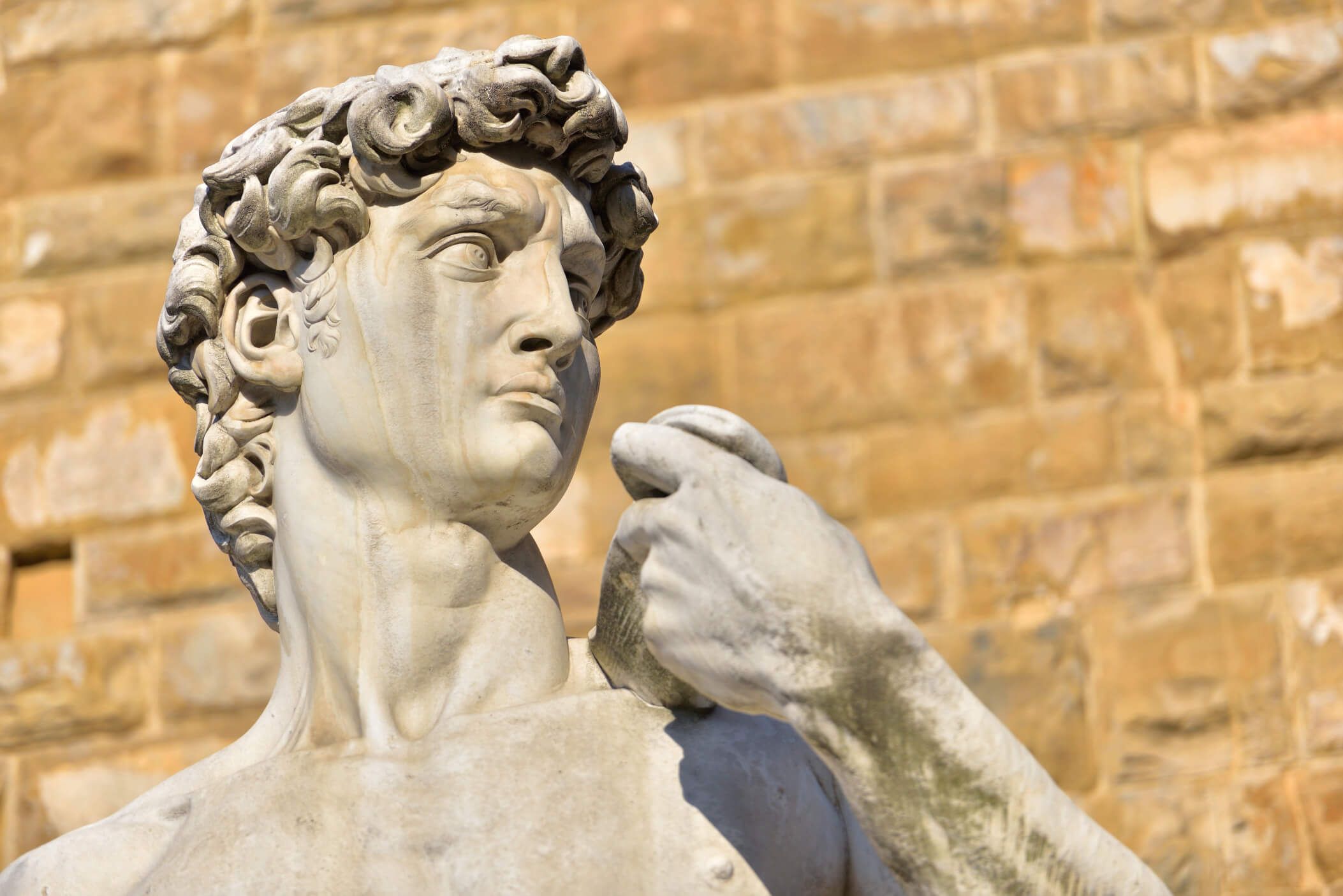 Die Skulptur zeigt einen jungen Mann mit strengen Gesichtszügen und lockigem Haar, aus Marmor gefertigt.