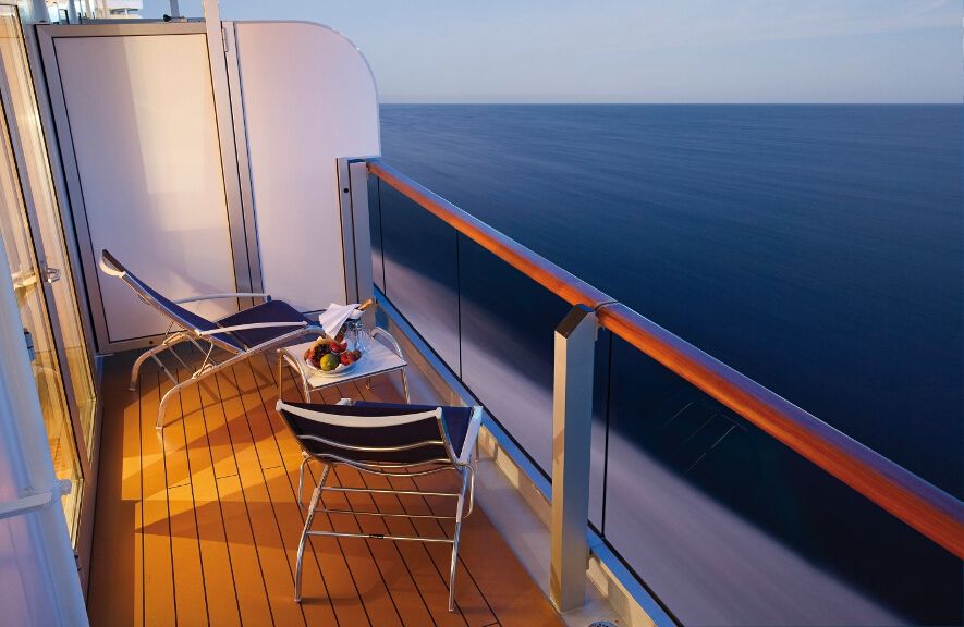 Ein Balkon auf einem Kreuzfahrtschiff mit Blick auf das ruhige Meer und einem Tisch mit frischem Obst.