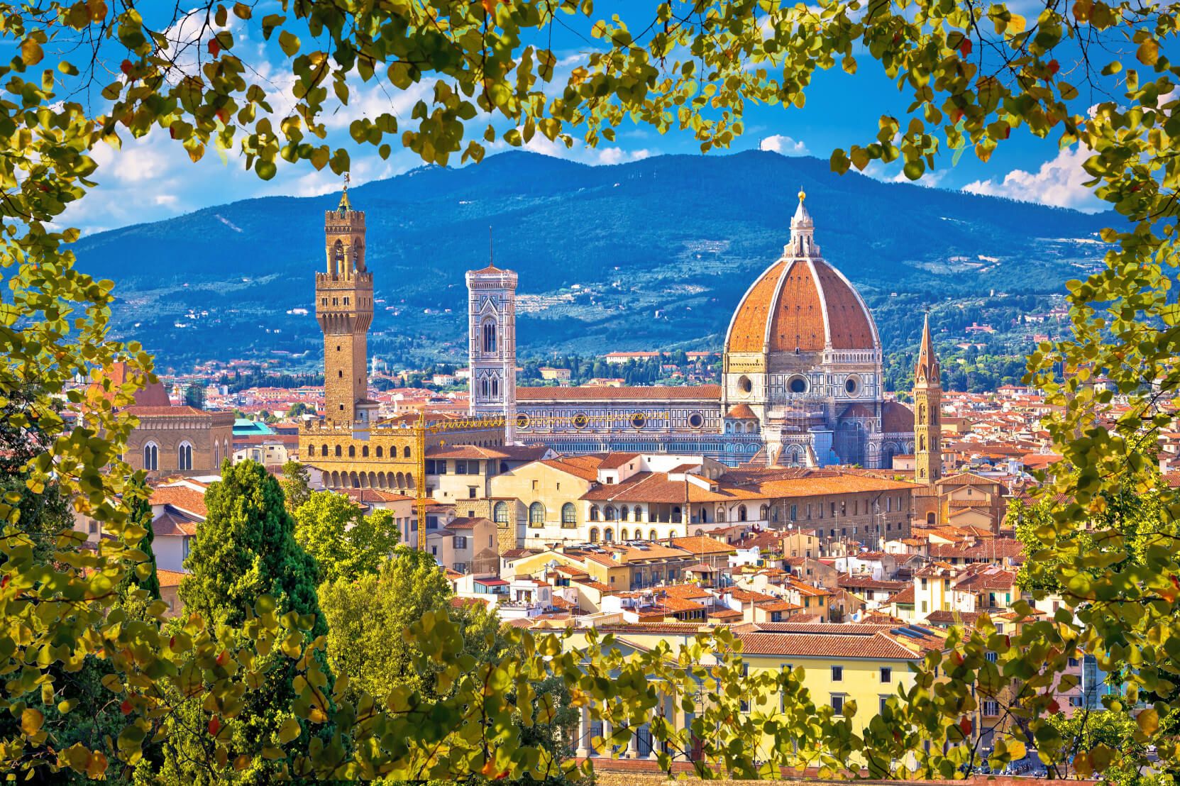 Blick auf Florenz mit der beeindruckenden Kathedrale und historischen Gebäuden, umrahmt von grünen Blättern.