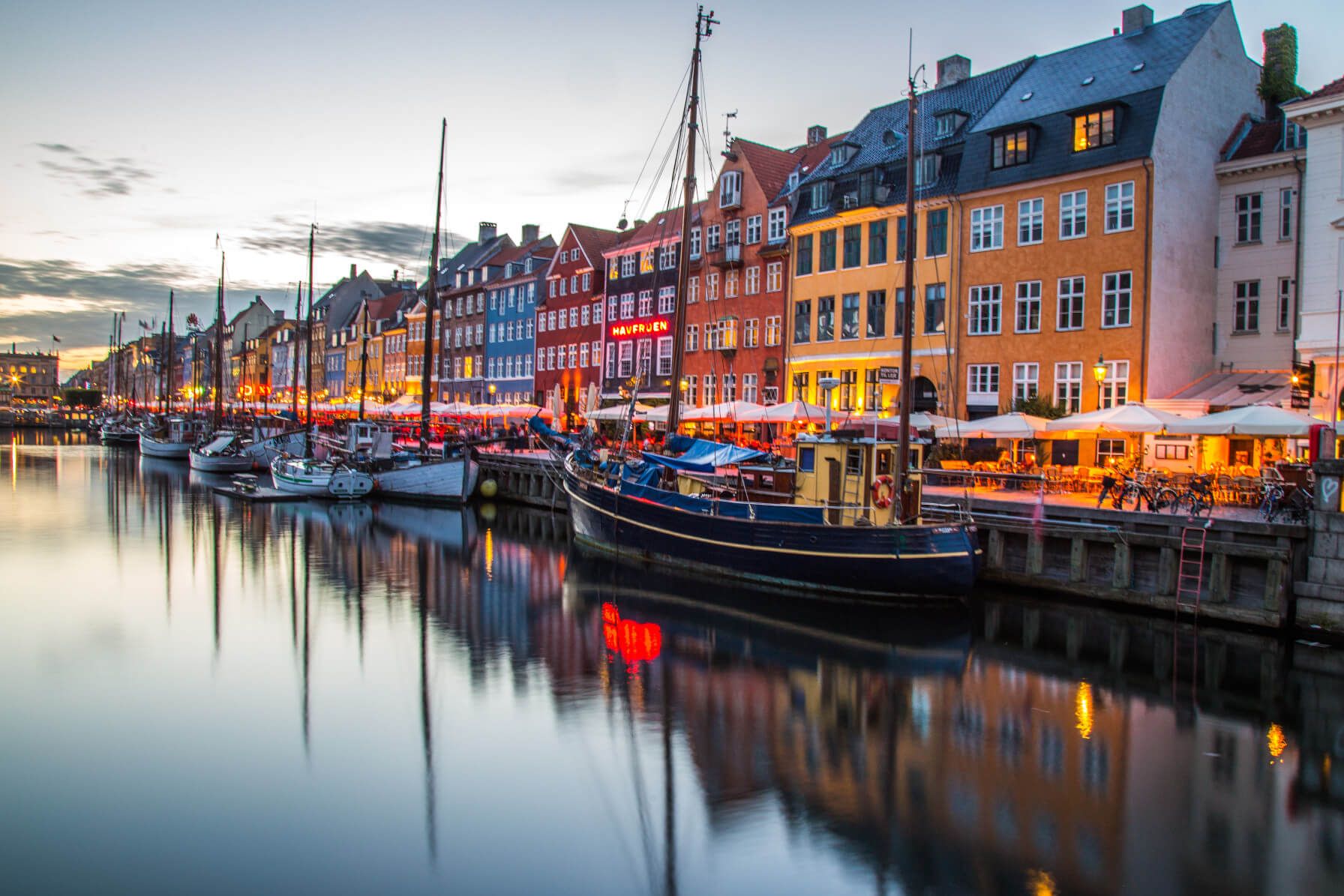 Bunte Häuser am Wasser, gemütliche Boote und beleuchtete Terrassen schaffen eine einladende Atmosphäre.