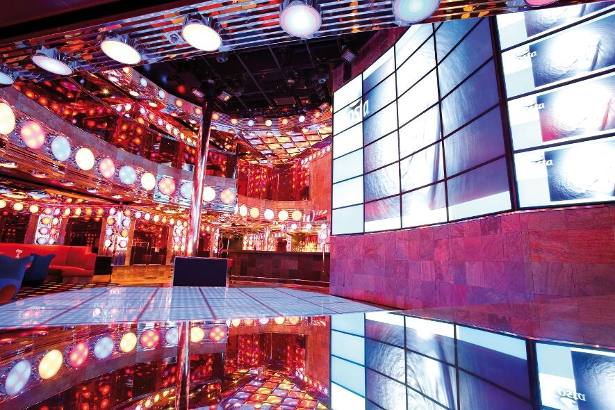 Eine stilvolle Lounge mit bunten Lichtern, Spiegeln und einer modernen Bar. Atmosphärische Stimmung zum Entspannen.