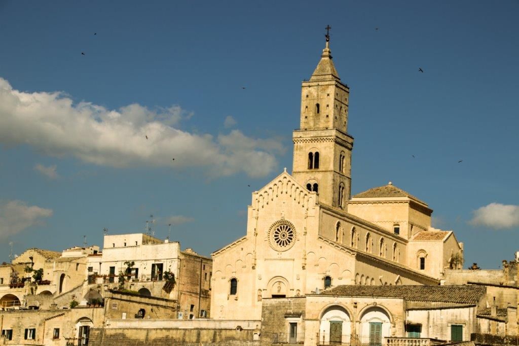 Eine historische Kirche mit charakteristischer Architektur unter blauem Himmel und einigen Wolken.