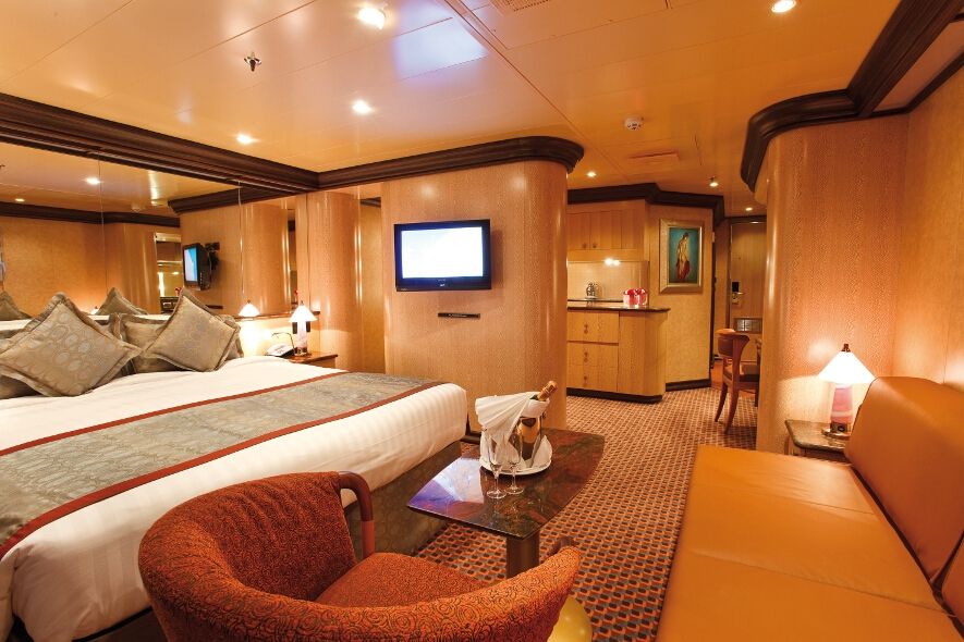 Ein elegantes, gemütliches Zimmer mit Doppelbett, Sofa, Fernseher und einer kleinen Sitzecke.