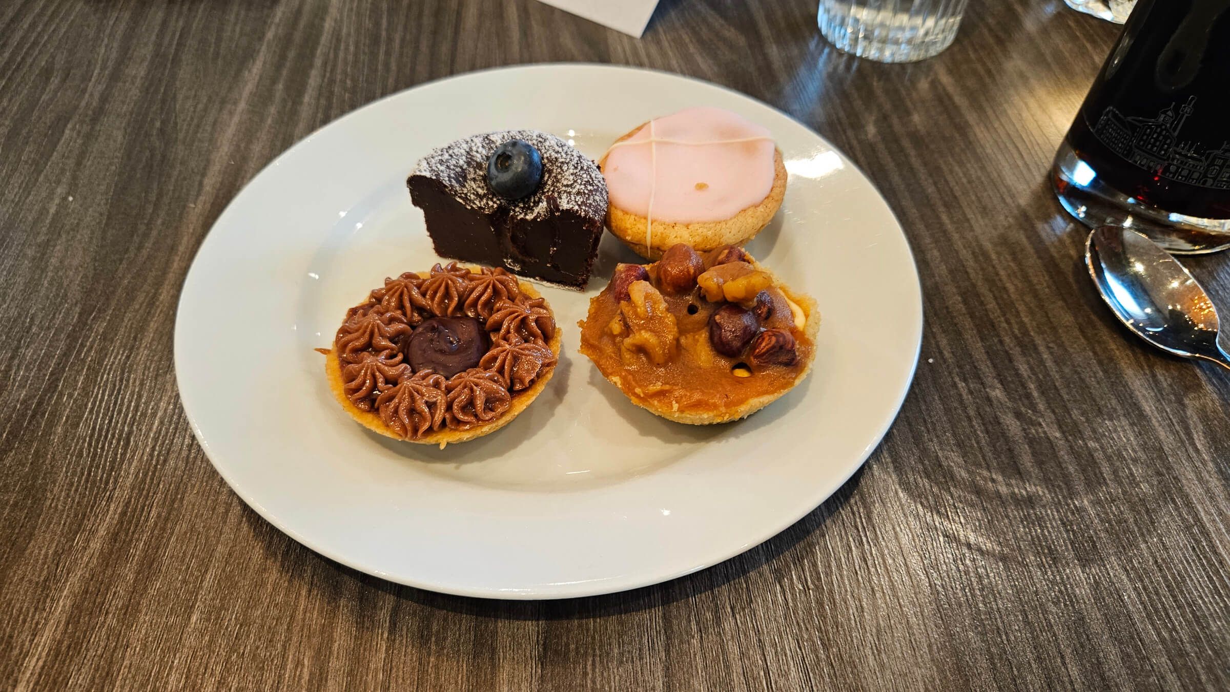 Auf einem Teller sind vier verschiedene kleine Kuchen und Törtchen, bunt dekoriert und appetitlich angerichtet.