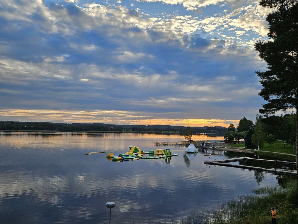 Ein ruhiger See bei Sonnenuntergang mit bunten Wasserattraktionen und idyllischer Umgebung.