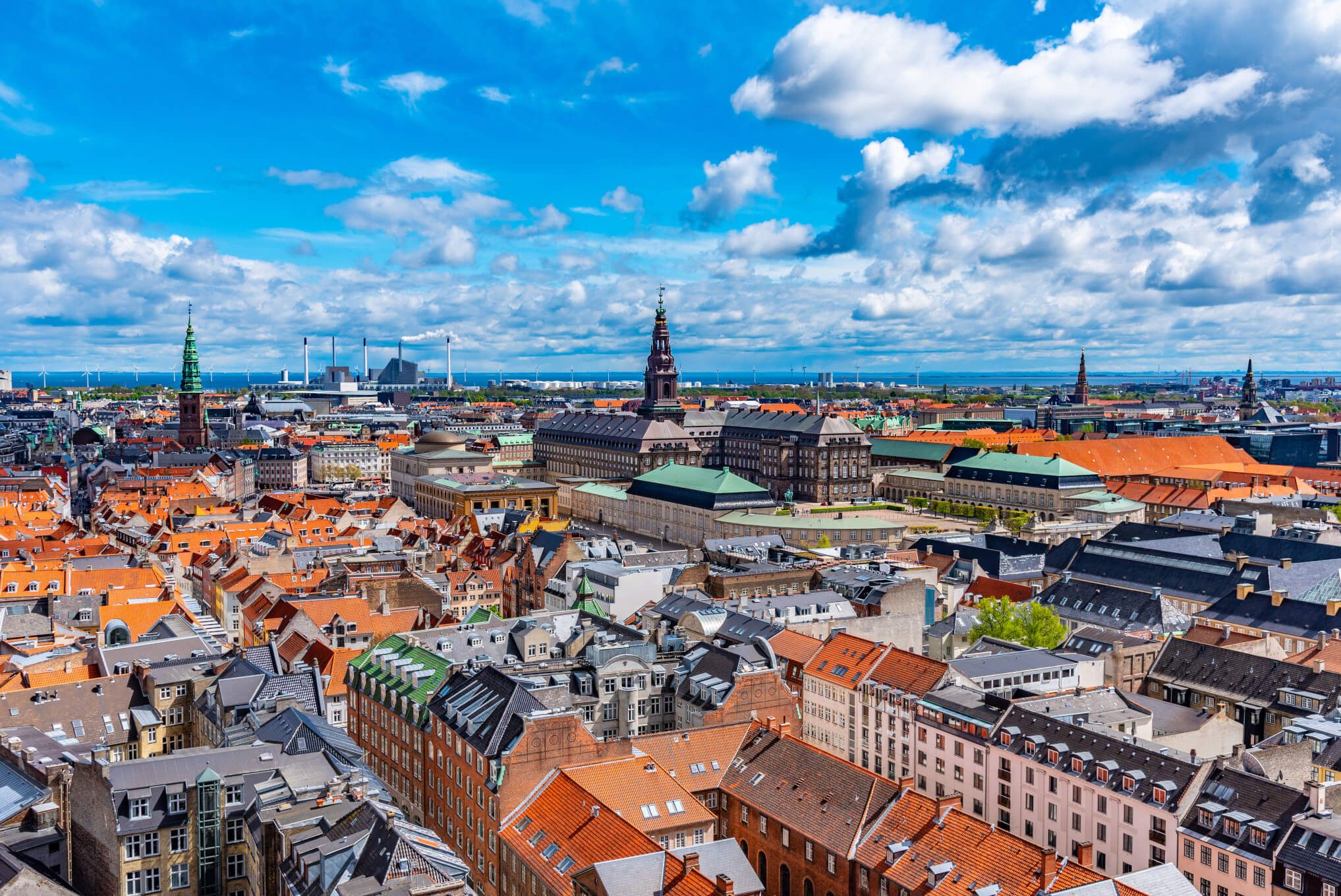 Ein Blick über Kopenhagen mit bunten Dächern, historischen Gebäuden und einem strahlend blauen Himmel.