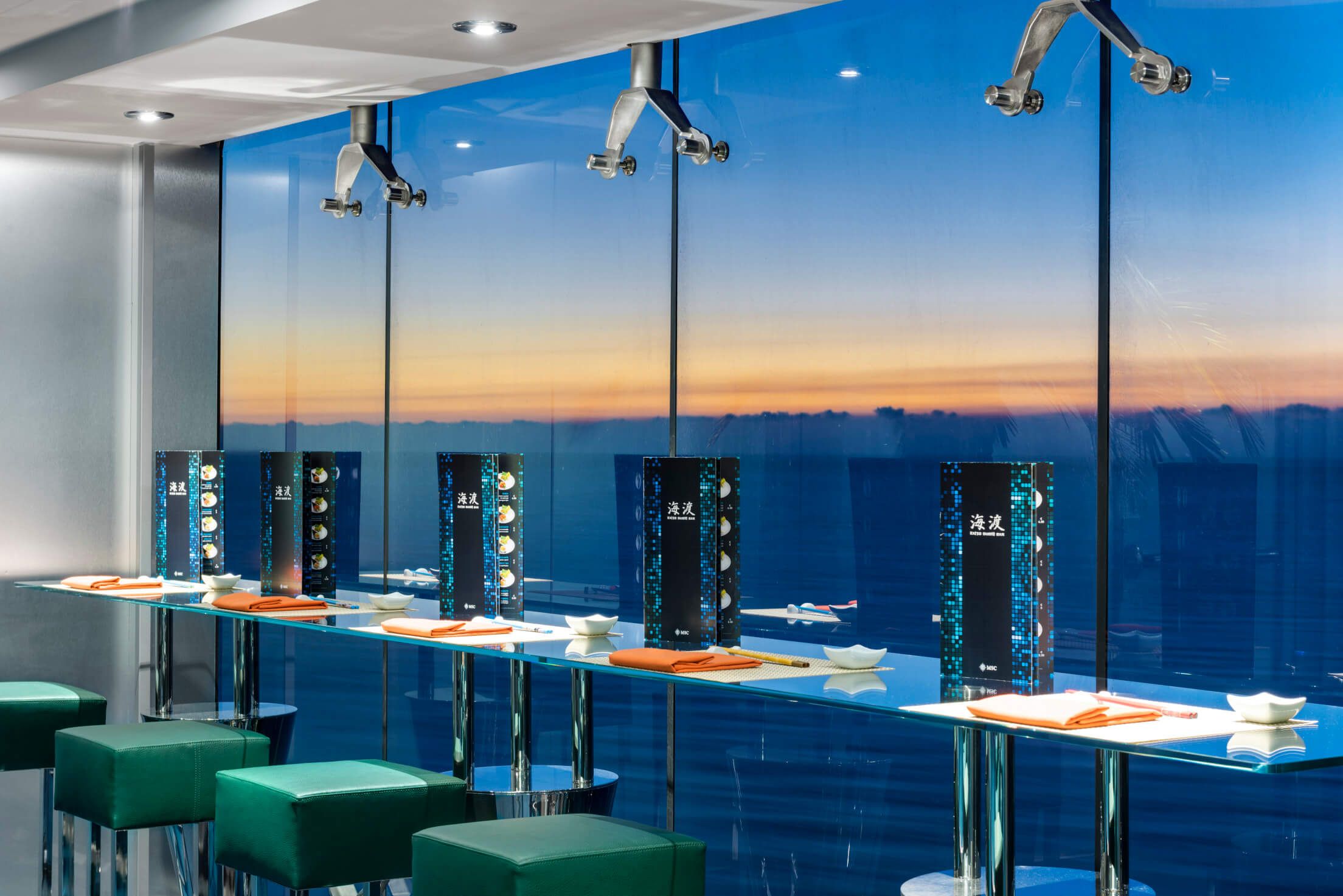 Moderne Restaurant-Innenansicht mit Blick auf den Sonnenuntergang und eleganten Menüs an der Theke.