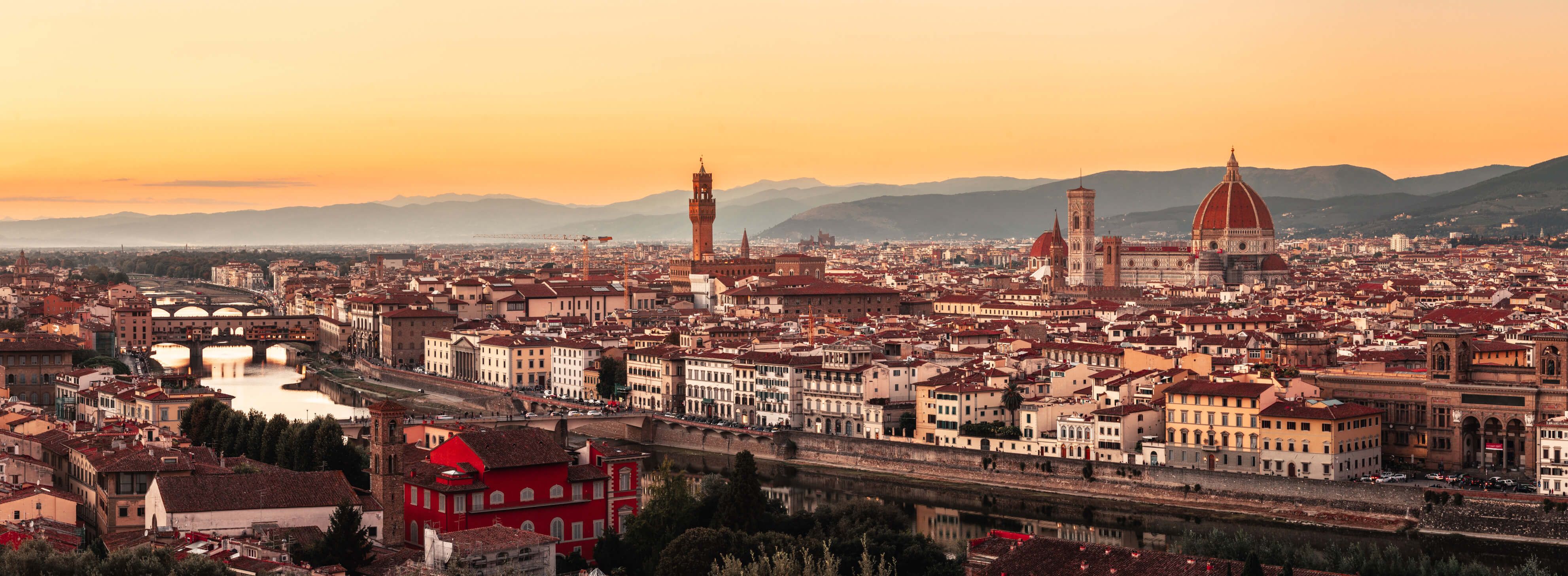 Eine traumhafte Panoramaansicht von Florenz bei Sonnenuntergang, die Architektur und den Fluss Arno zeigt.