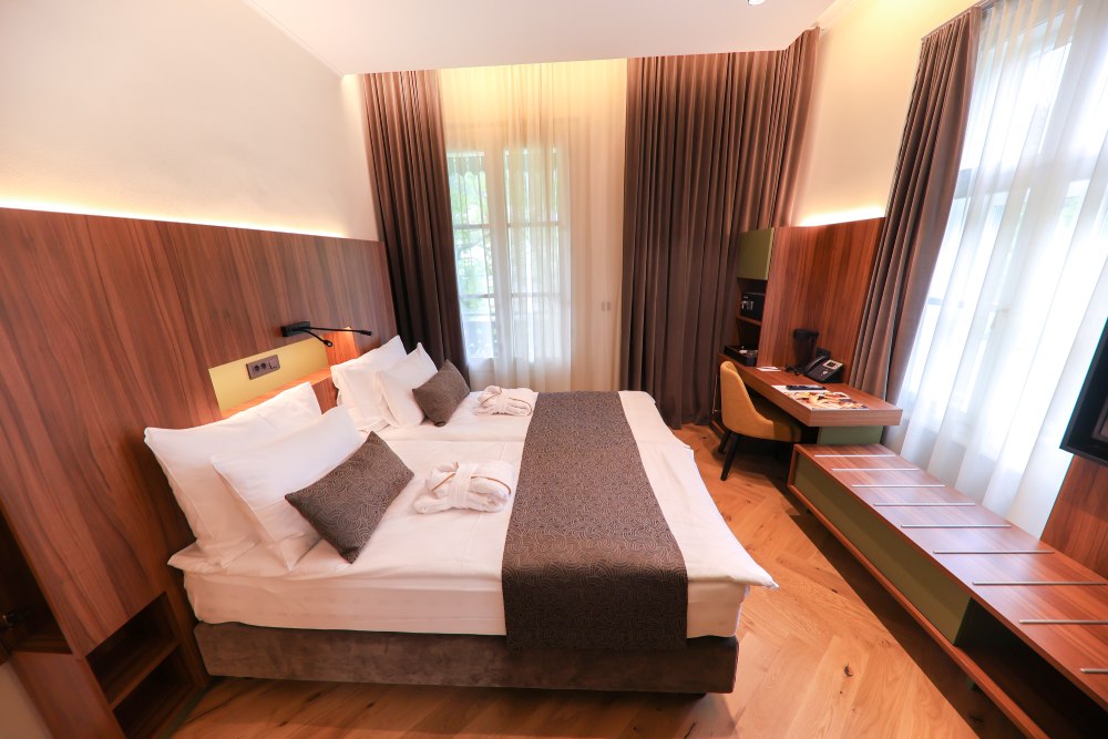 Ein modernes, elegantes Hotelzimmer mit zwei Betten, Schreibtisch und großen Fenstern für viel Tageslicht.