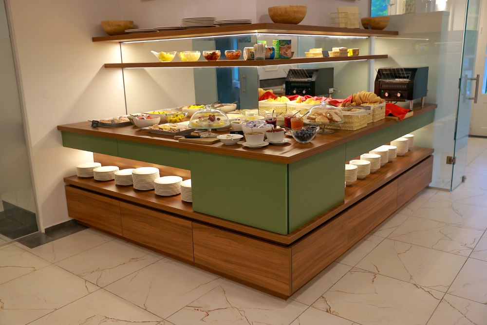 Ein Buffet mit einer Vielzahl von Speisen, Brötchen und Tellern in einem eleganten, modernen Raum.