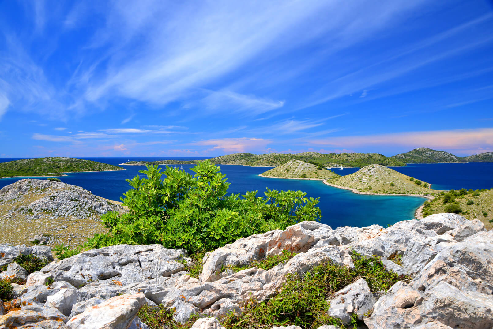 Eine atemberaubende Aussicht auf eine Küstenlandschaft mit grünen Inseln und klarem blauen Wasser unter einem strahlend blauen Himmel.