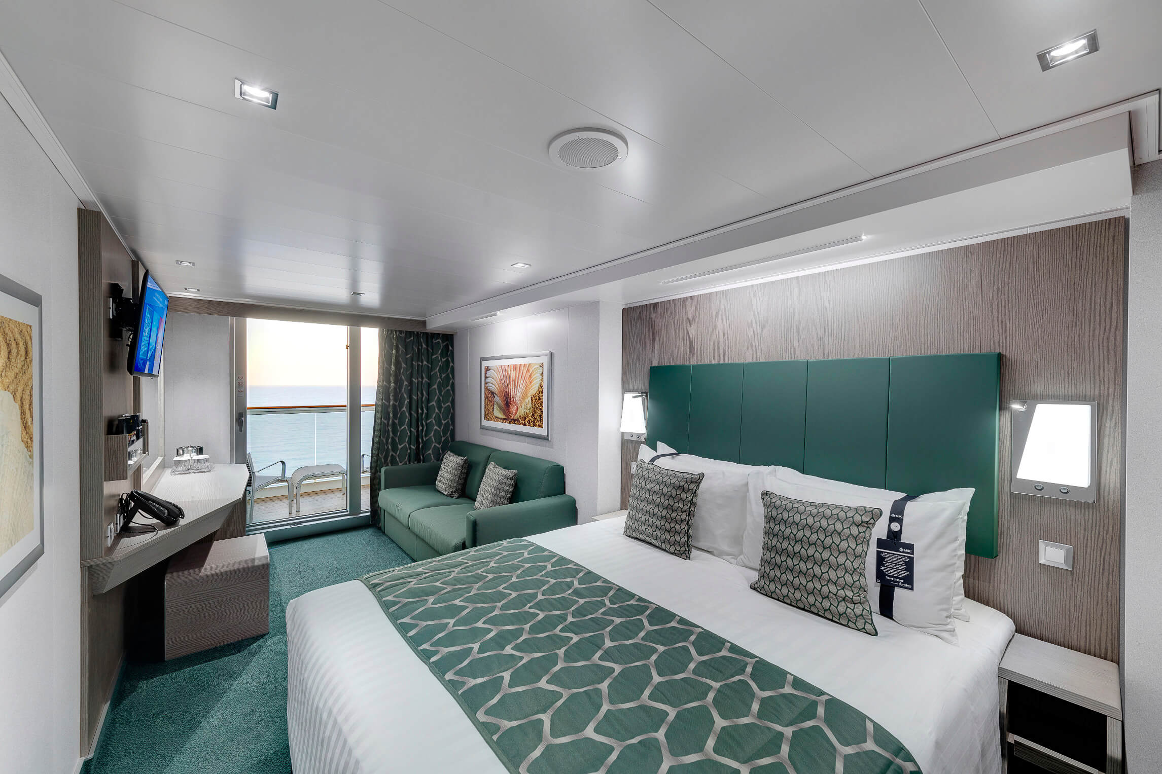 Ein modernes Zimmer mit Balkon, Meerblick, Doppelbett, Sofa und TV. Helle Farben und stilvolle Einrichtung.