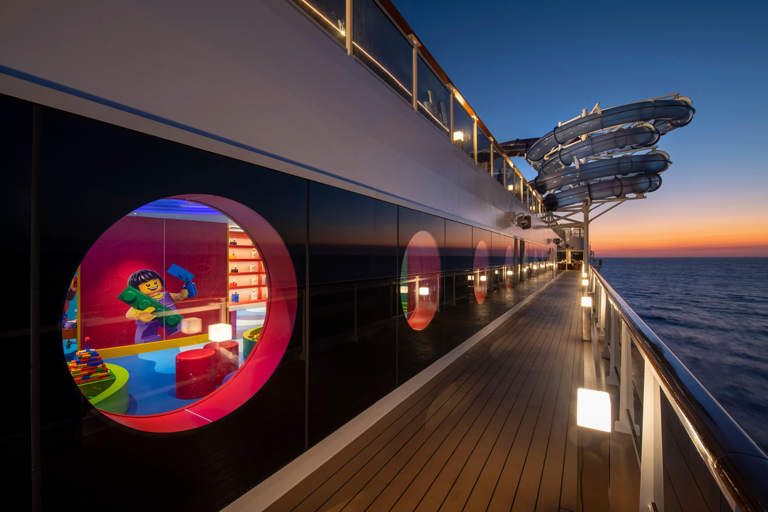Ein Blick auf ein Kreuzfahrtschiff mit einer bunten Spielstation für Kinder und traumhaftem Sonnenuntergang.