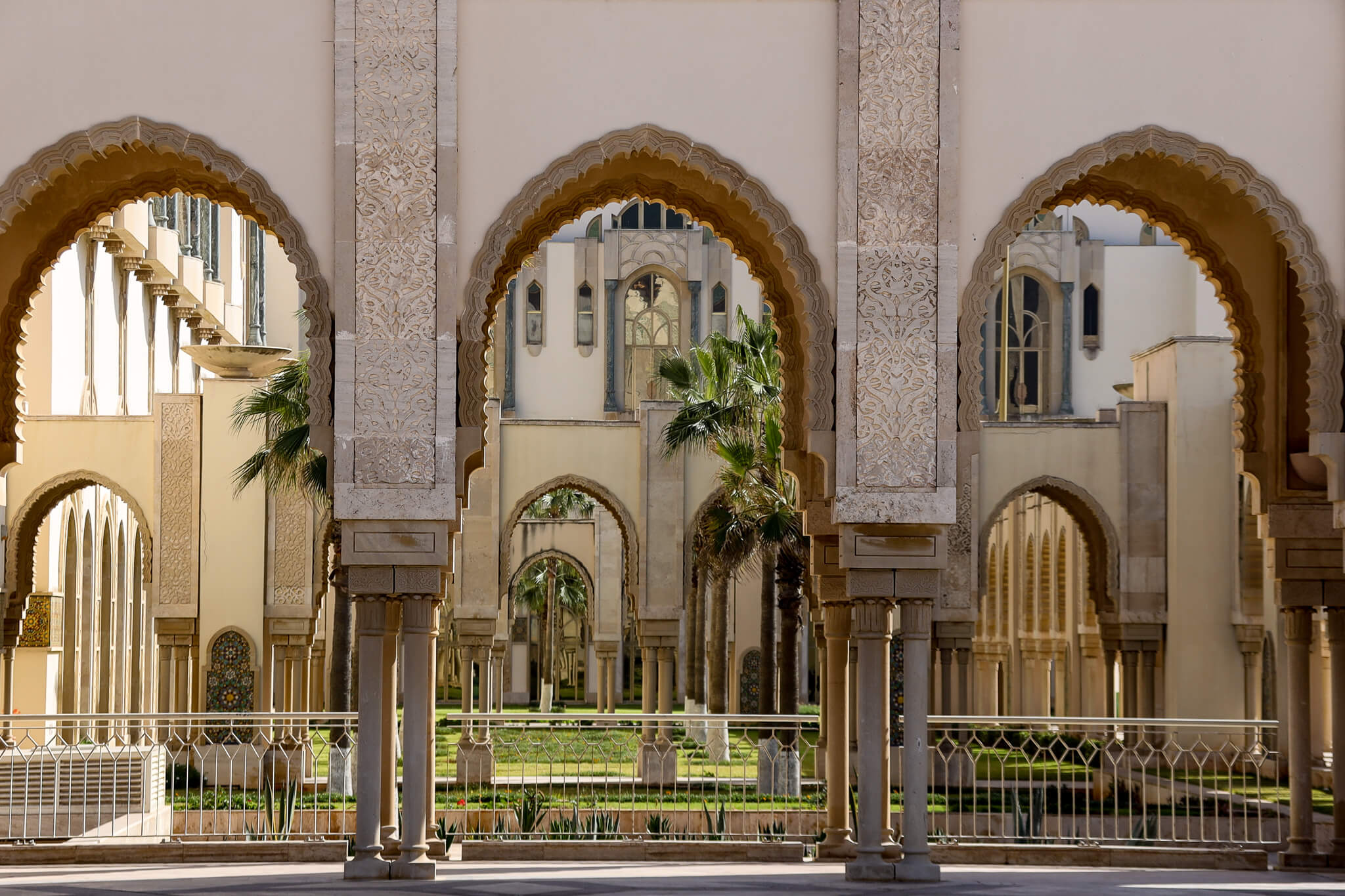 Ein architektonisches Ensemble mit eleganten Bögen und grünen Palmen im Hintergrund.