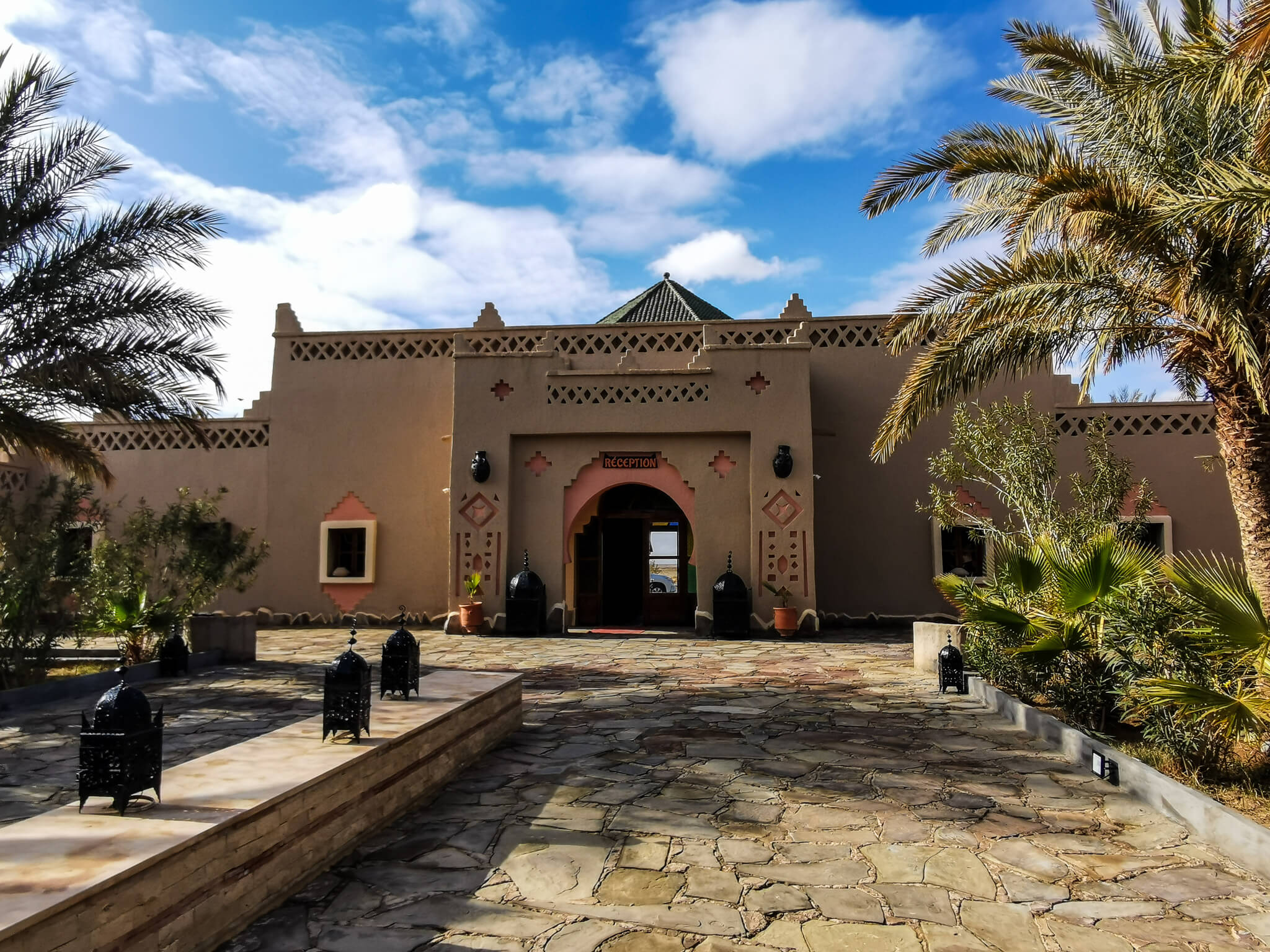 Ein traditionelles Gebäude mit arabischer Architektur, umgeben von Palmen und einem schönen Himmel.