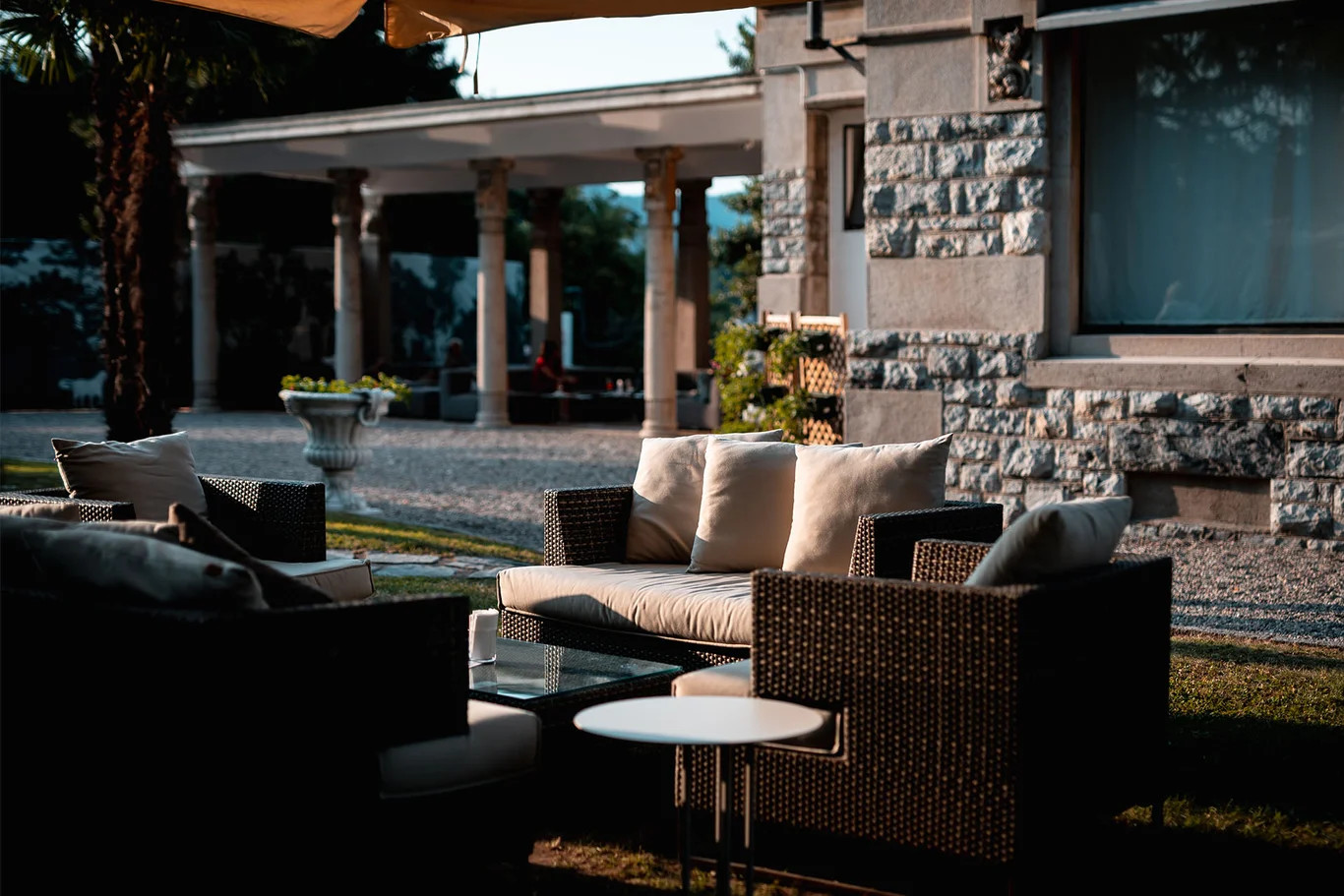 Ein eleganter Außenbereich mit stilvollen Möbeln, umgeben von Palmen und einem modernen Gebäude im Hintergrund.