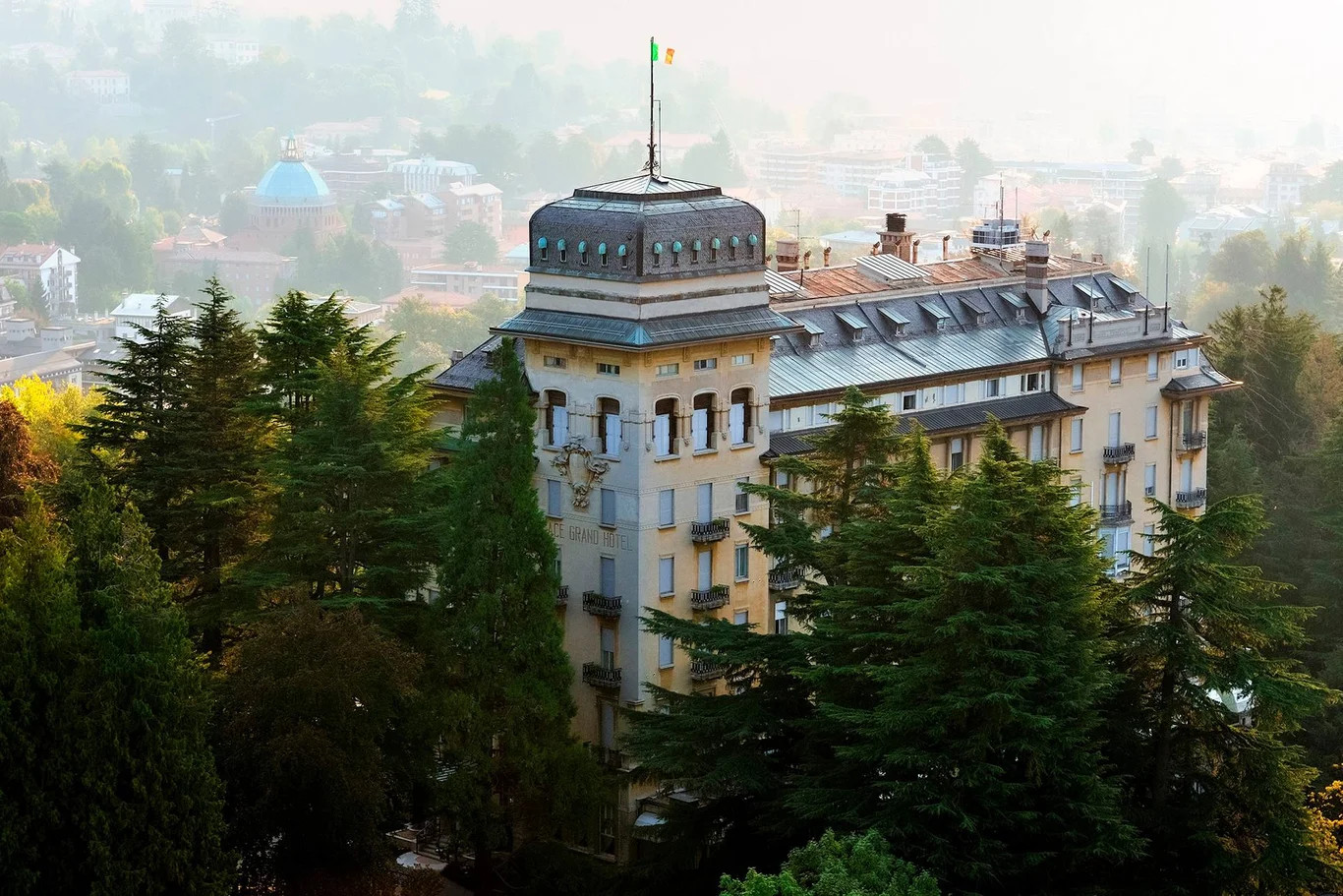 Ein prächtiges Gebäude umgeben von Bäumen, mit einer Fahne auf dem Dach und einer malerischen Aussicht.