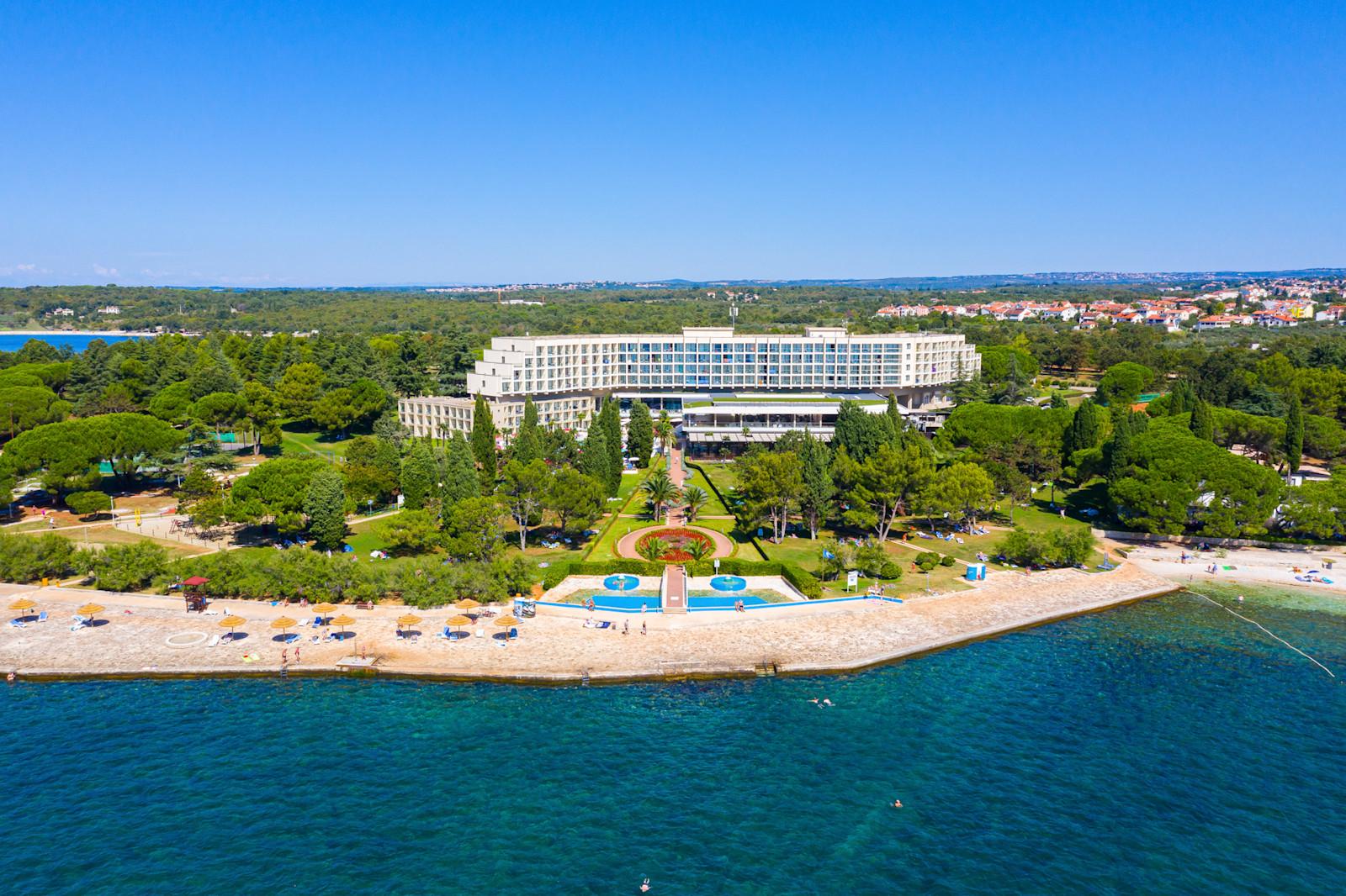 Ein wunderschöner Küstenblick mit einem Hotel, Strandabschnitten und grünen Parks unter klarem Himmel.