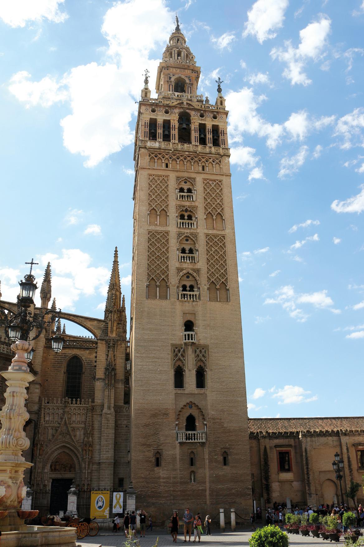 Der beeindruckende Giralda-Turm in Sevilla, umgeben von historischer Architektur und blauer Himmel.