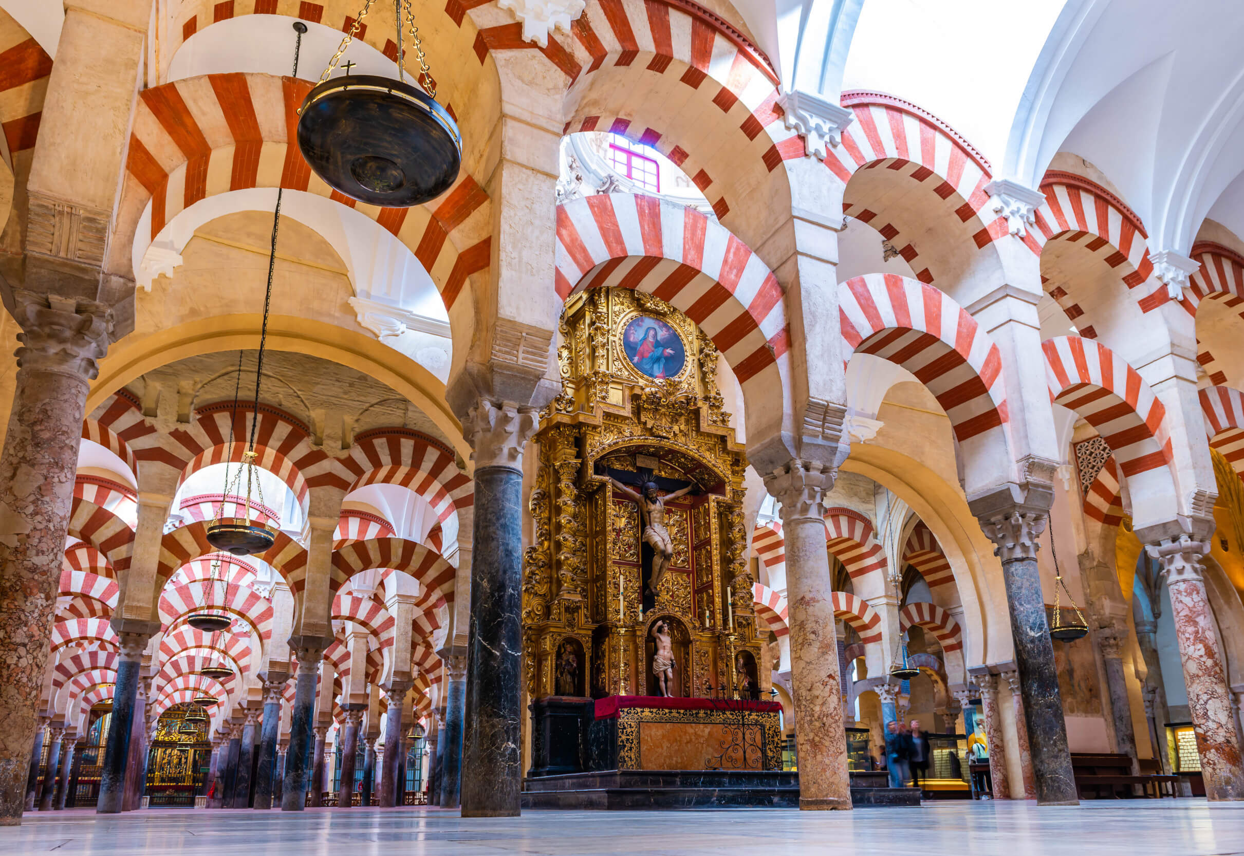 Das Bild zeigt eine beeindruckende Architektur mit roten und weißen Bögen in einem historischen Innenraum.