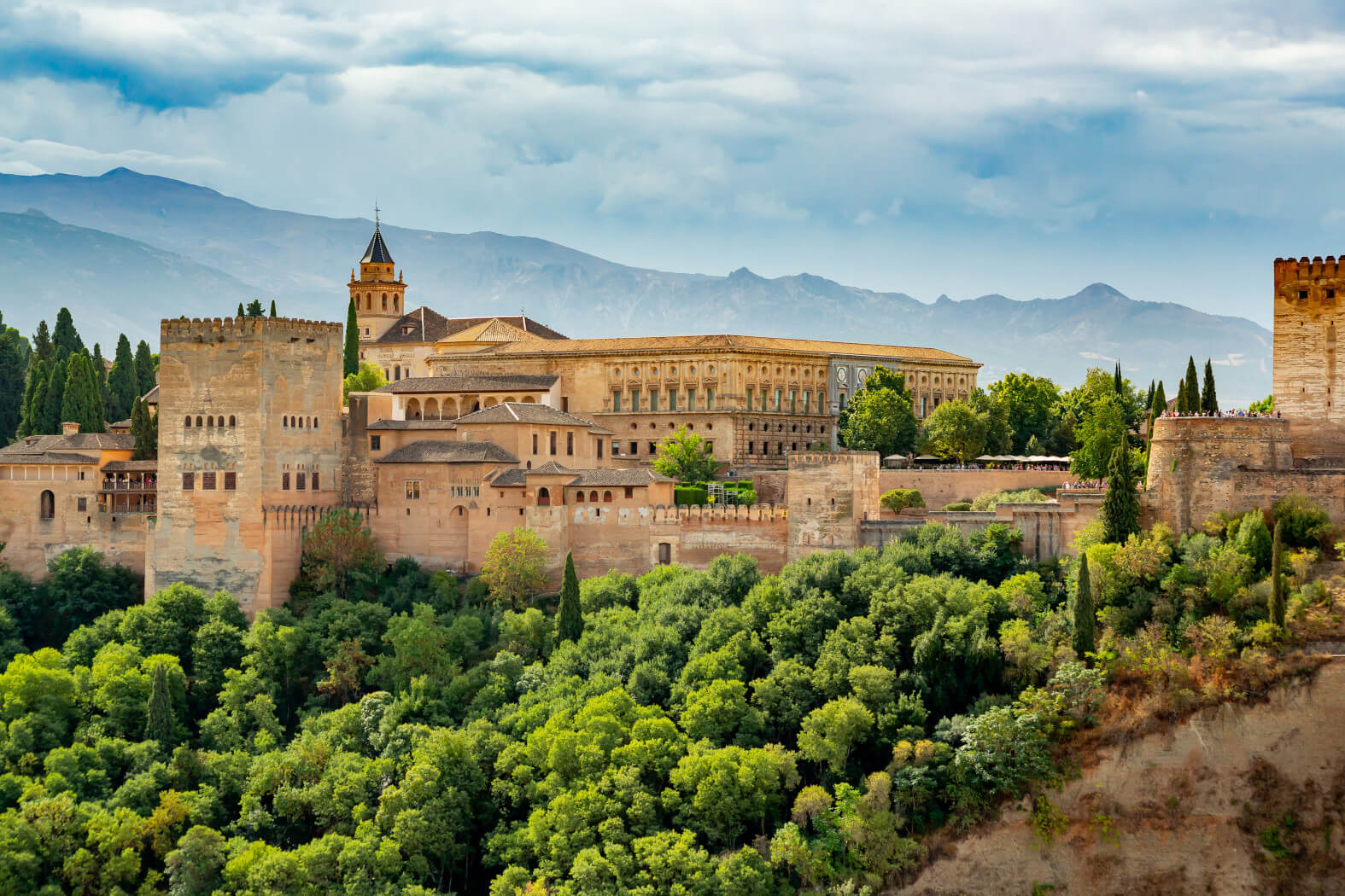 Die Alhambra in Granada, umgeben von üppigem Grün und herrlichem Gebirgen, strahlt historische Pracht aus.