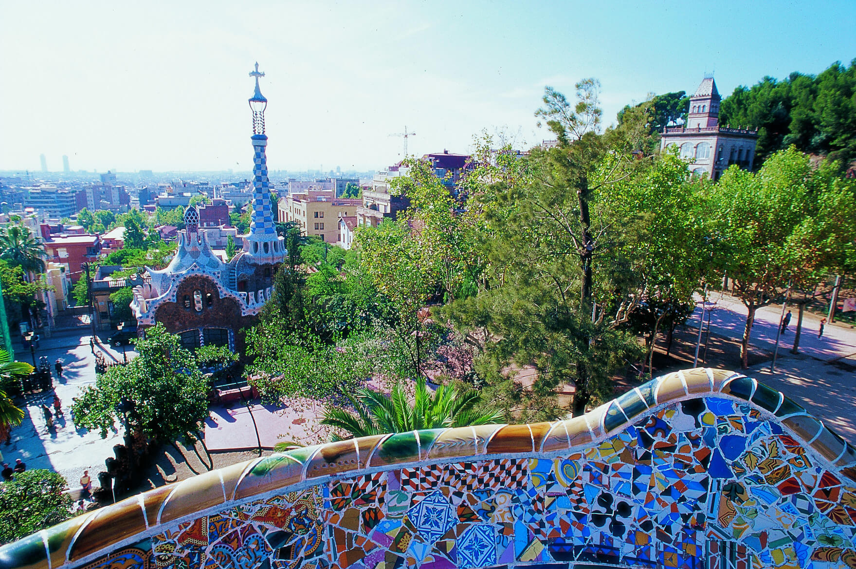 Ein schöner Blick auf den Park Güell in Barcelona mit bunten Mosaiken und viel grüner Natur.