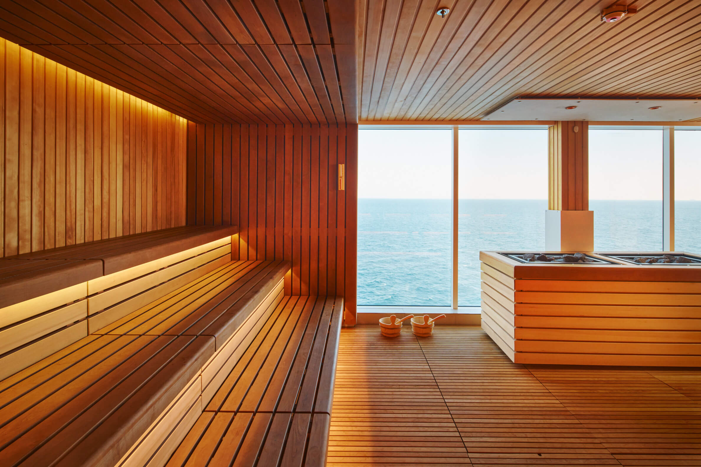 Eine moderne Sauna mit Holzverkleidung und Blick auf das Meer. Entspannende Atmosphäre und sanftes Licht.