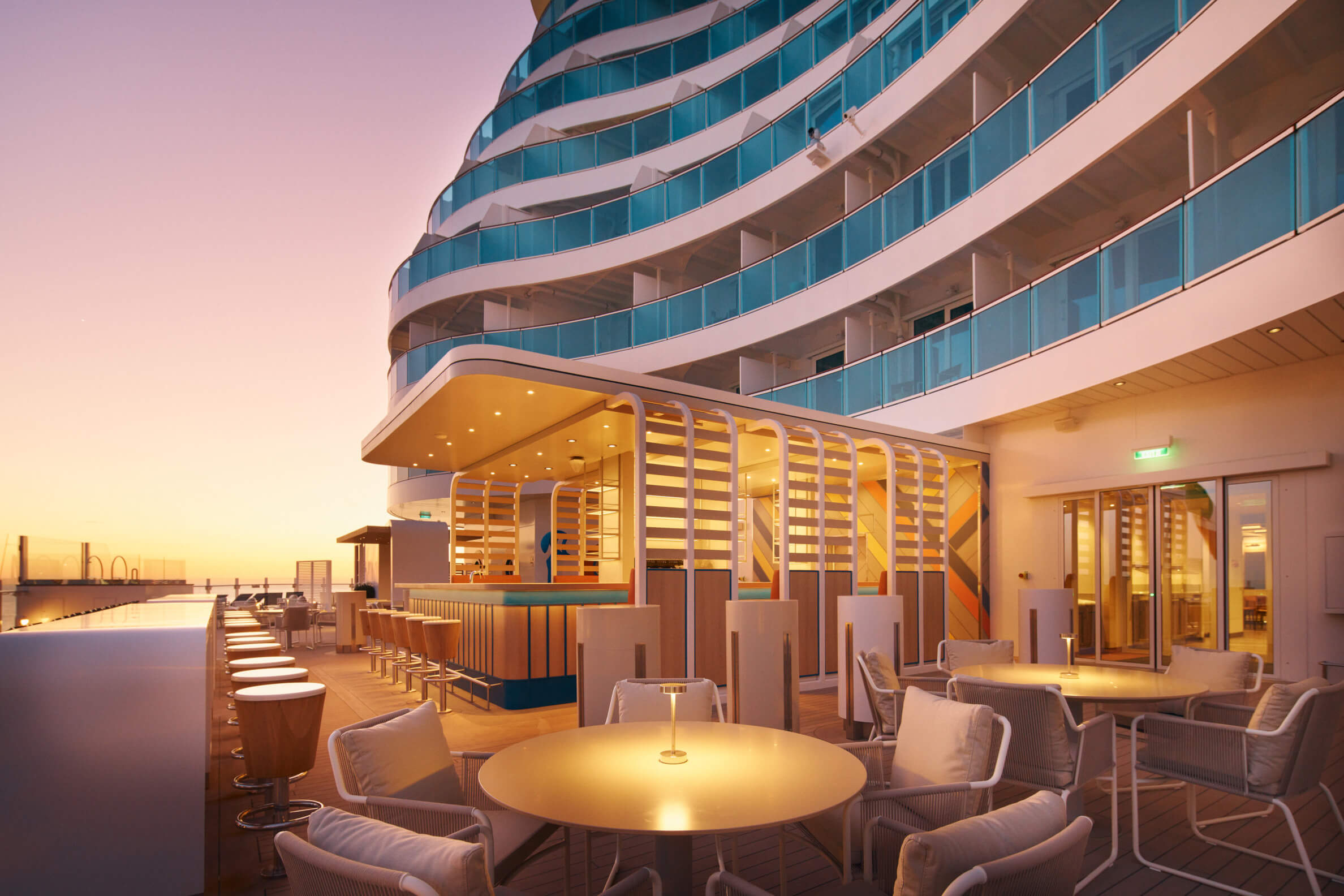 Moderne Terrasse eines Schiffes bei Sonnenuntergang mit gemütlichen Sitzplätzen und einer Bar.