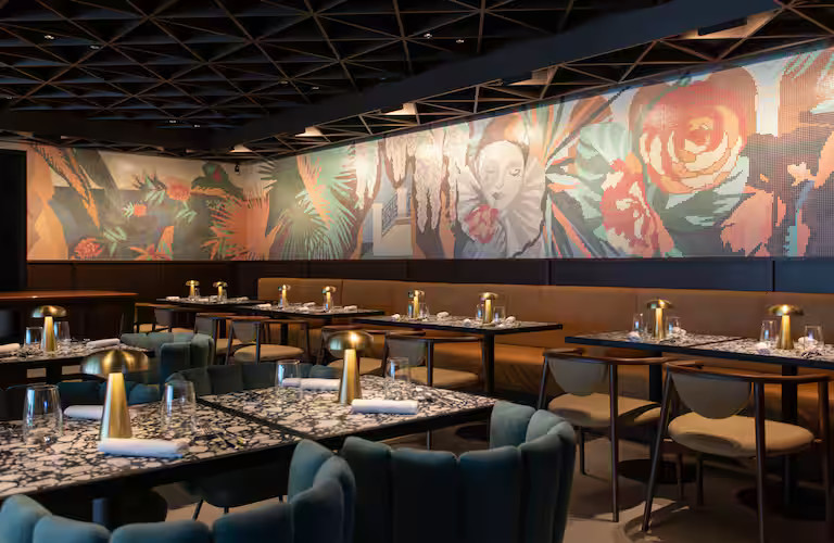 Elegante Restaurant mit modernen Tischen, stilvollen Stühlen und einer farbenfrohen Wandgestaltung.