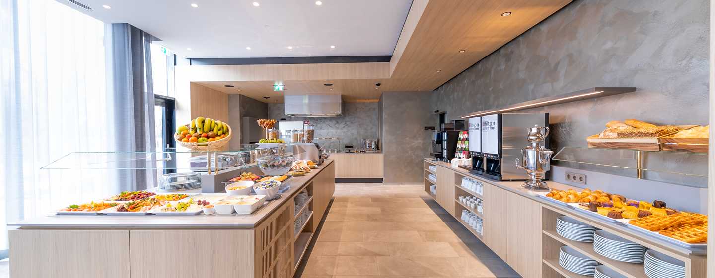 Ein modernes Frühstücksbuffet mit Obst, Gebäck und verschiedenen Speisen in einem einladenden Raum.