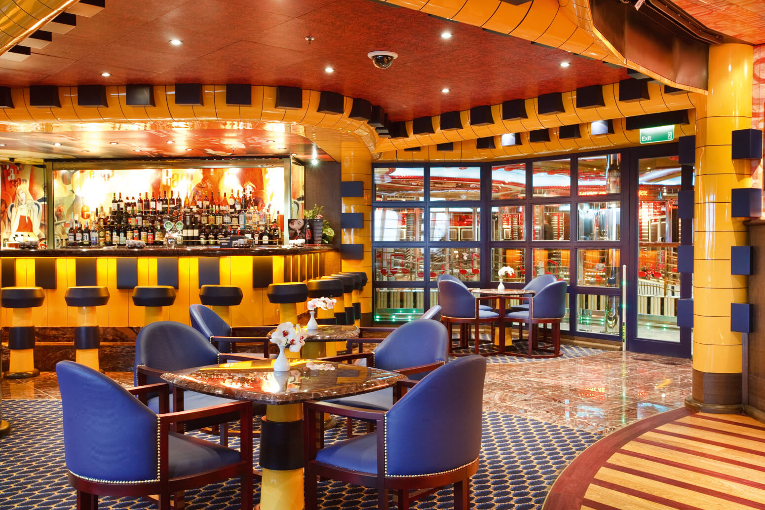 Eine stilvolle Bar mit bunten Wänden, eleganten Tischen und Stühlen, die eine einladende Atmosphäre bietet.