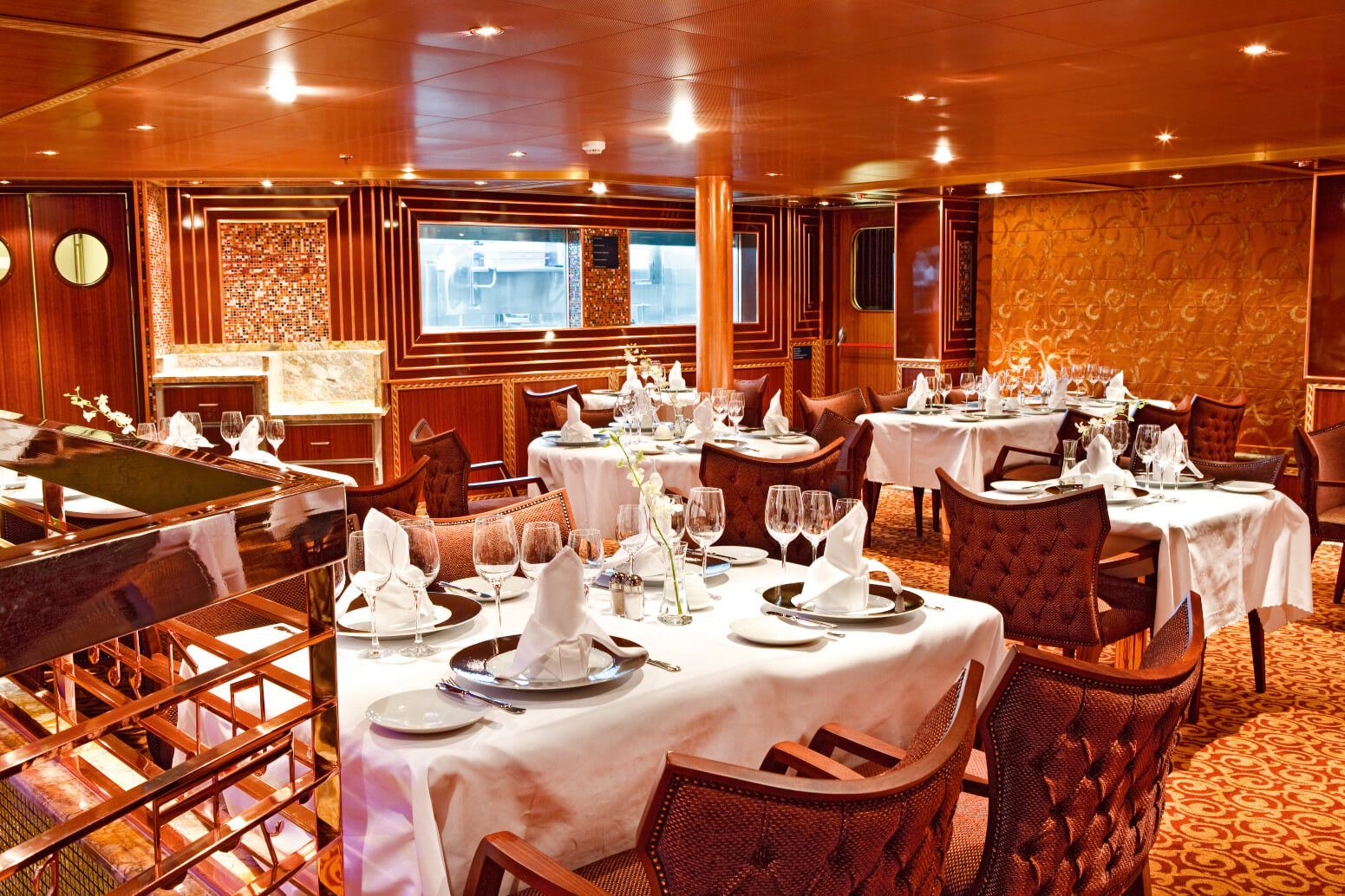 Elegantes Restaurant mit gedeckten Tischen, edlem Holzdesign und gedämpfter Beleuchtung. Einladende Atmosphäre.