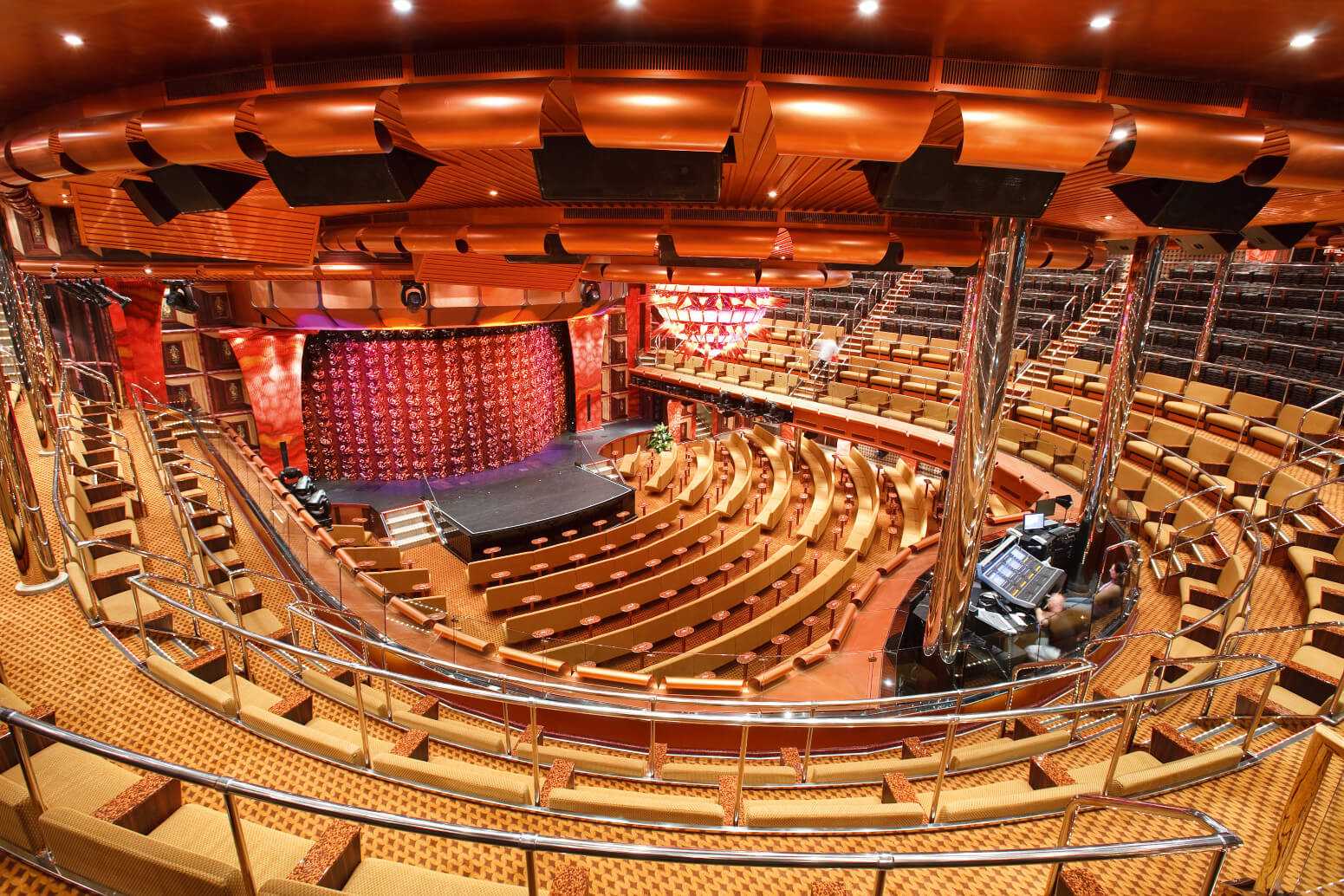 Ein modernes Theater mit vielen Reihen an Sitzen und einer Bühne, elegant in warmen Farben gestaltet.
