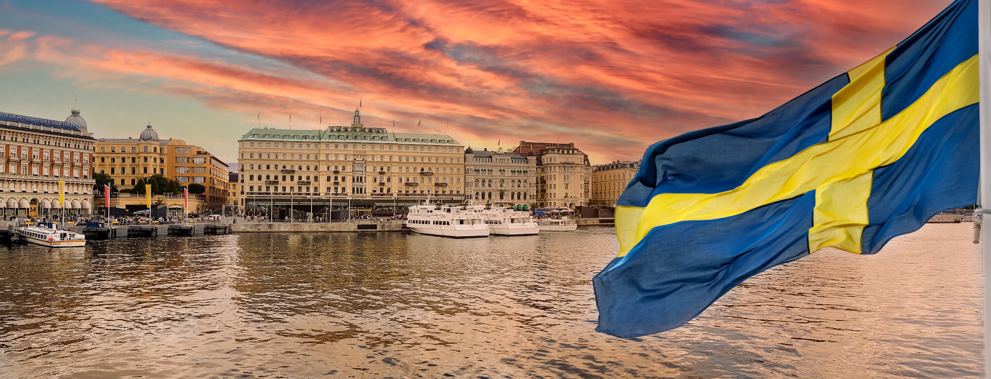 Eine malerische Stadtansicht mit schwedischer Flagge, einer Hafenpromenade und einem schönen Sonnenuntergang.