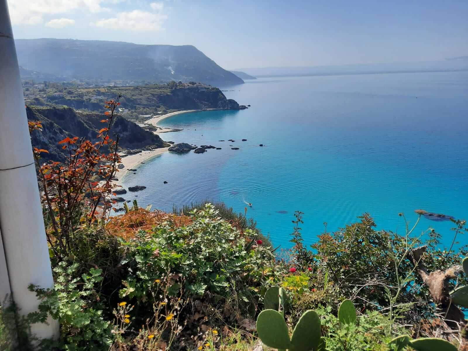 Eine atemberaubende Küstenlandschaft mit klarem, blauem Wasser und üppiger Vegetation an den Felsen.