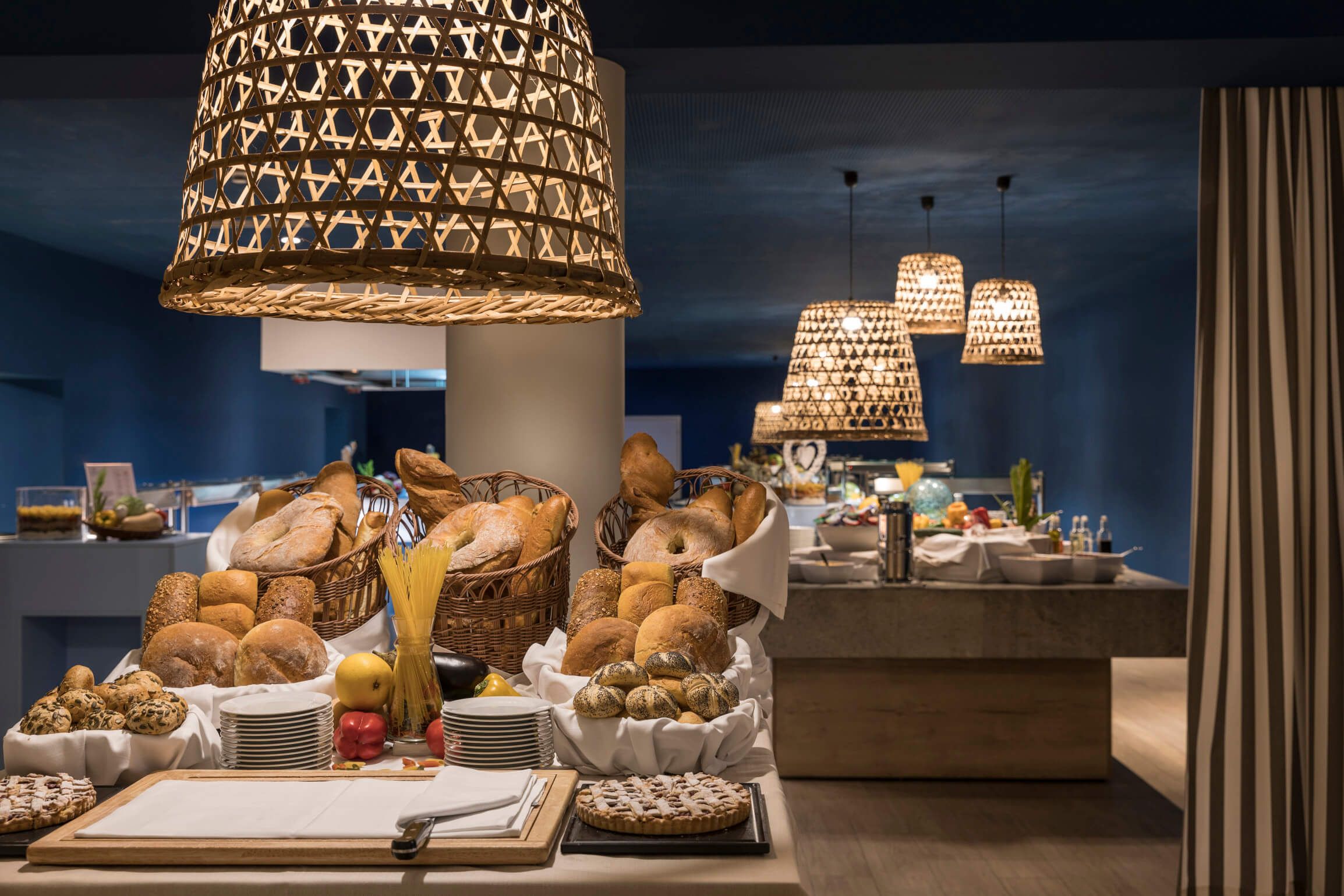 Ein schön dekorierter Frühstücksbuffet-Bereich mit frischem Brot und ansprechenden Leckereien unter stilvollen Lampen.