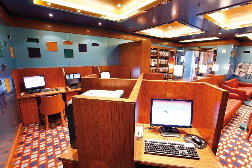 Ein moderner Computerraum mit Holztrennwänden, Schreibtischen und gemütlichen Sitzecken.