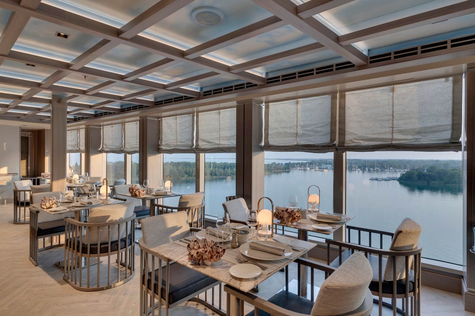 Moderne Restaurant mit Panoramablick auf einen See, stilvolle Tische und elegante Einrichtung.