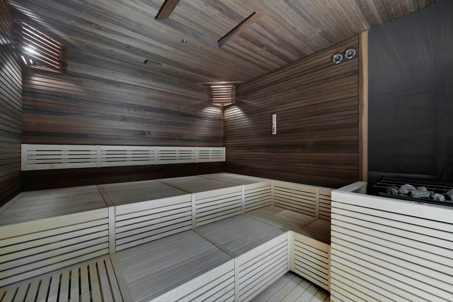 Moderne Sauna mit Holzverkleidung, beleuchtet und geräumig, ideal zum Entspannen und Wohlfühlen.