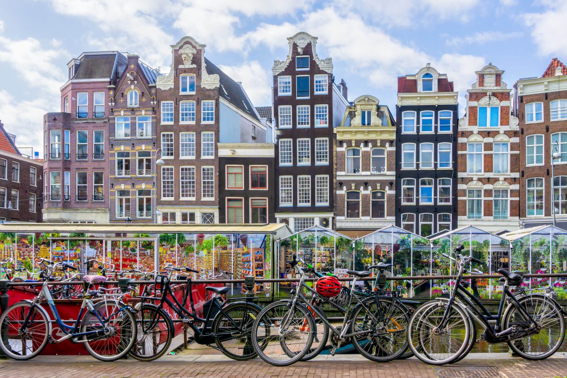 Bunte, historische Gebäude und viele Fahrräder am Kanal in Amsterdam unter einem klaren Himmel.