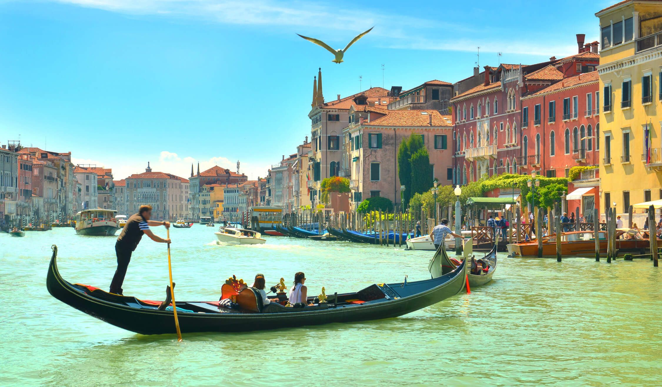 Venedigs Kanal mit Gondeln, bunten Gebäuden und Sonnenlicht, perfekt für eine ruhige Bootsfahrt und Entspannung.