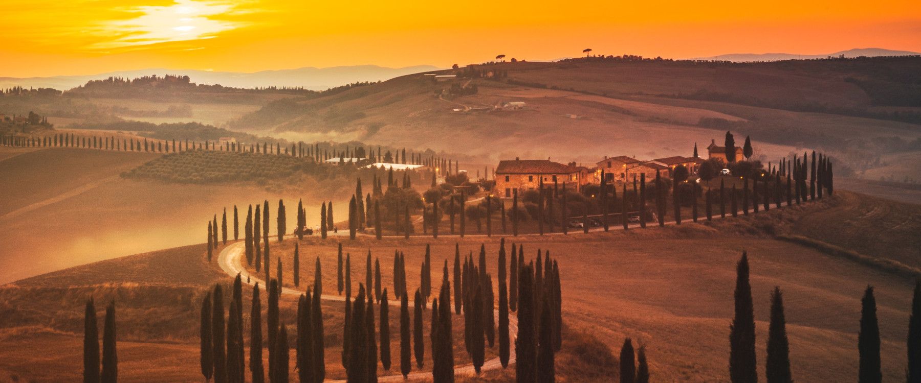 Sanfte Hügel, Zypressen und ein malerischer Sonnenuntergang über toskanischer Landschaft. Ruhe und Schönheit vereint.