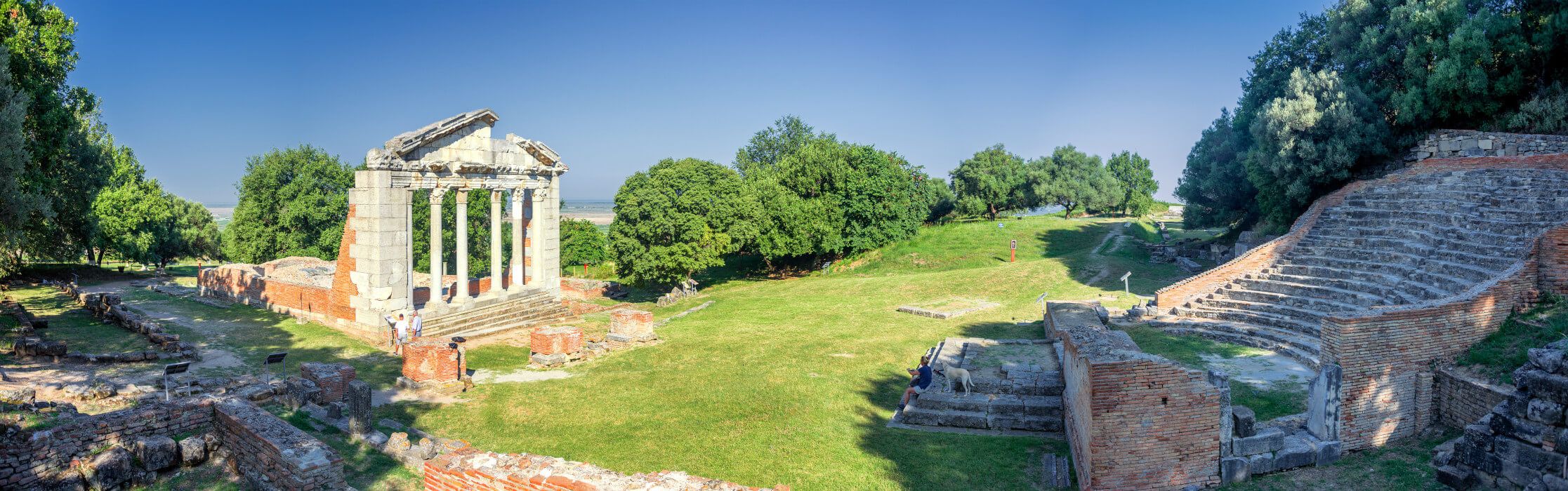 Ruinen einer antiken Tempelanlage umgeben von Bäumen und einer großen Wiese, ideal für Erkundungen und Ruhe.