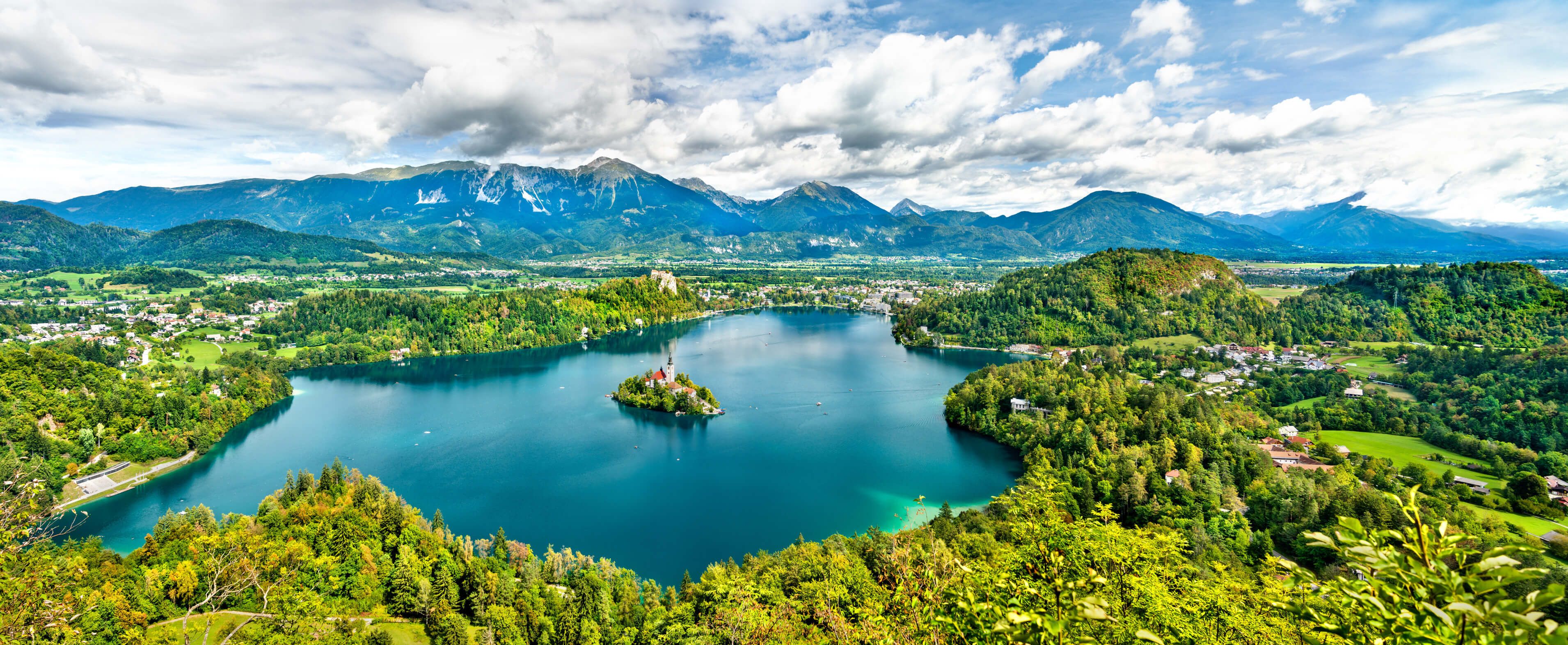 Ein atemberaubender Blick auf den Bleder See, umgeben von Bergen und üppigem Grün. Ein malerisches Landschaftsbild.