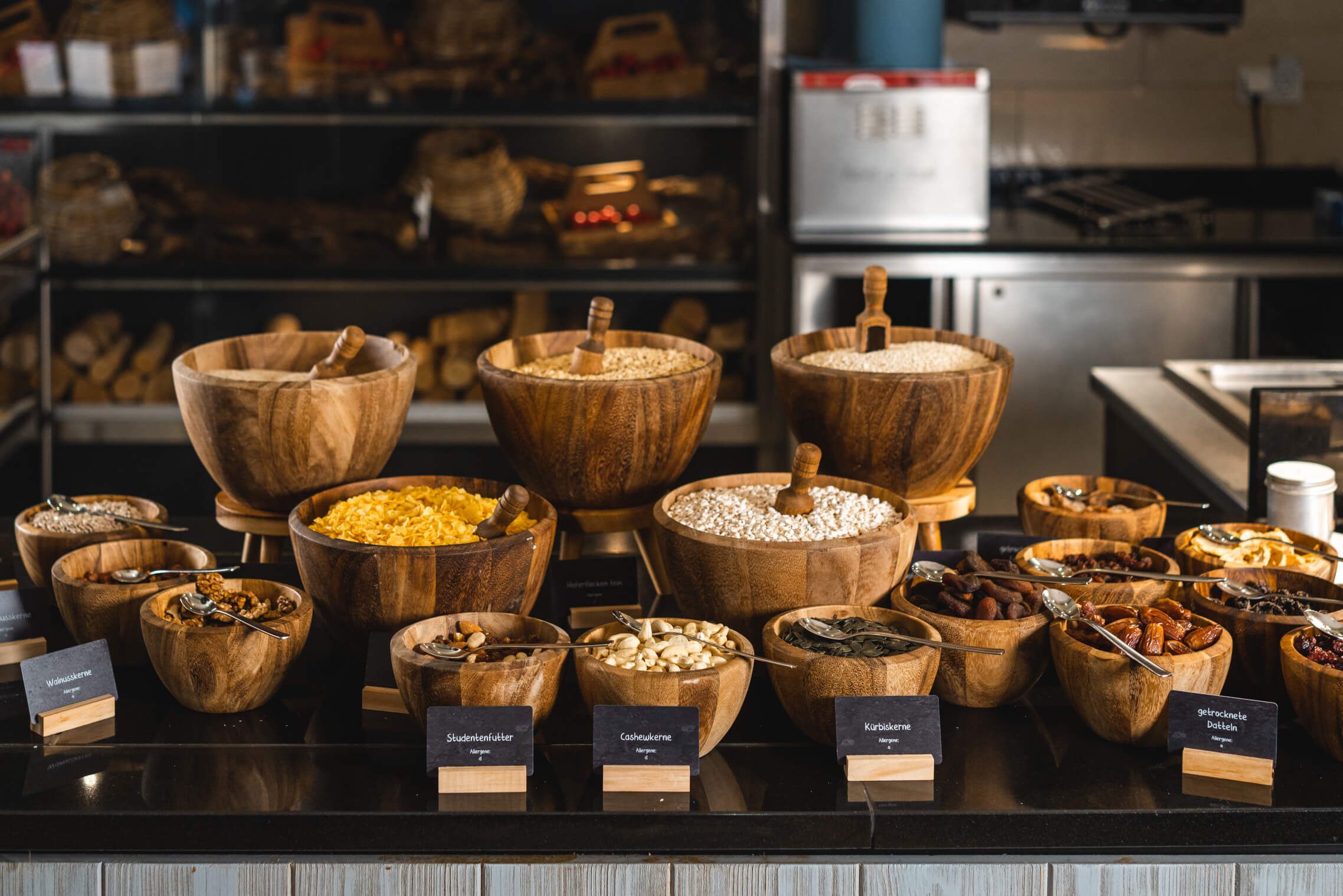 Eine Auswahl an Gewürzen und Snacks in Holzschalen, liebevoll angerichtet in einem modernen Küchenumfeld.
