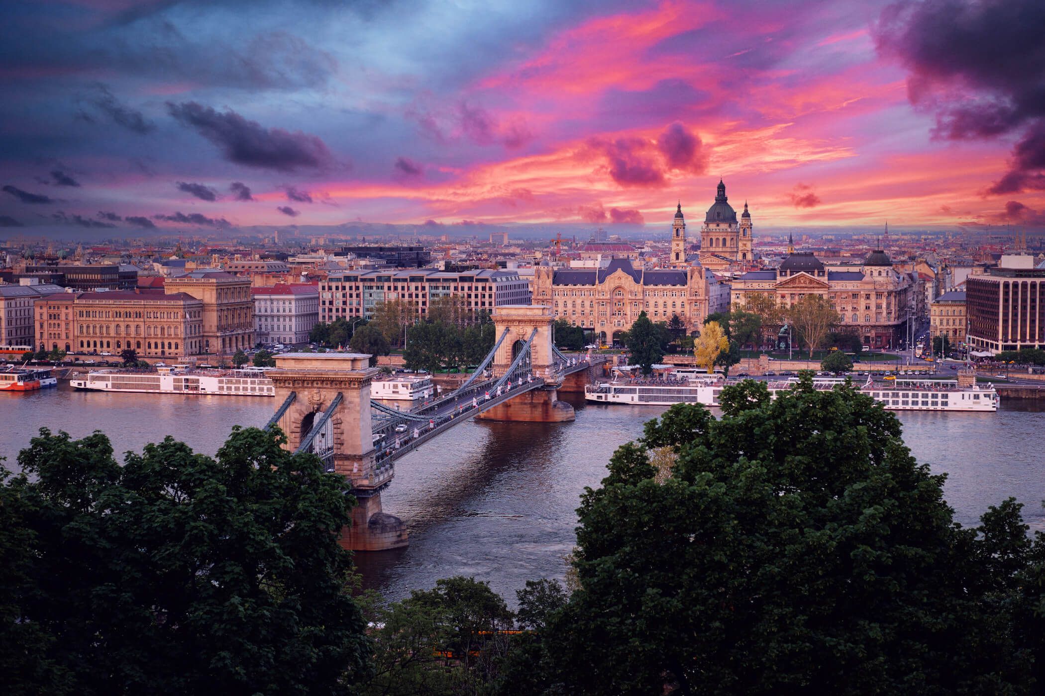 Die Kettenbrücke in Budapest bei Sonnenuntergang, umgeben von beeindruckender Architektur und lebhaften Farben.