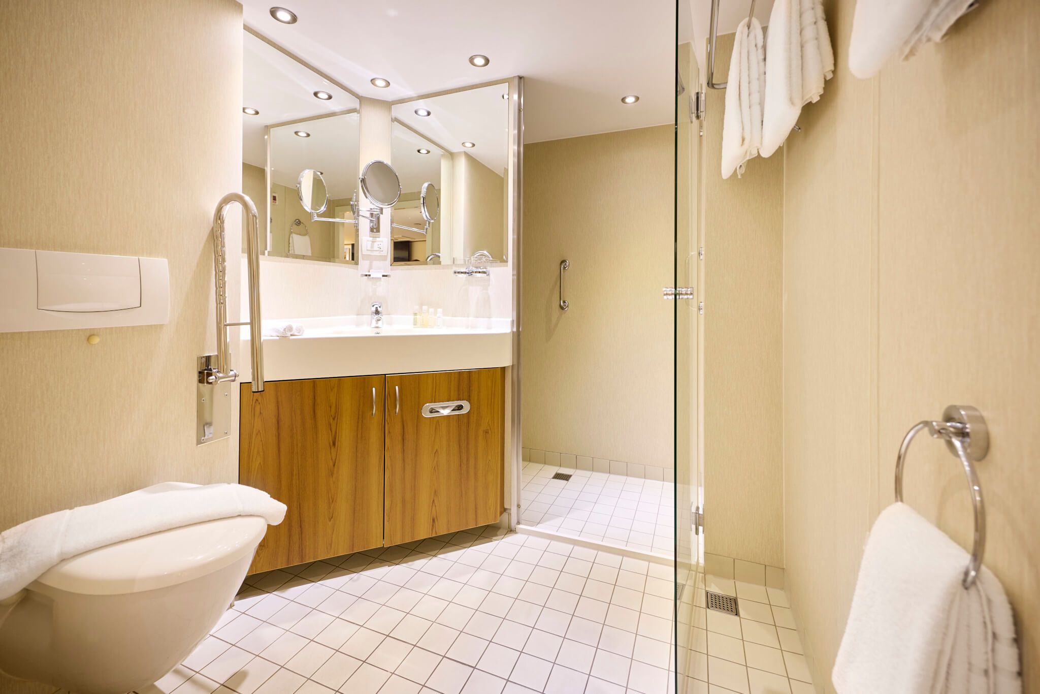 Modernes Badezimmer mit Dusche, Waschbecken, Holzschränken und fliesenboden. Hell erleuchtet und ordentlich.