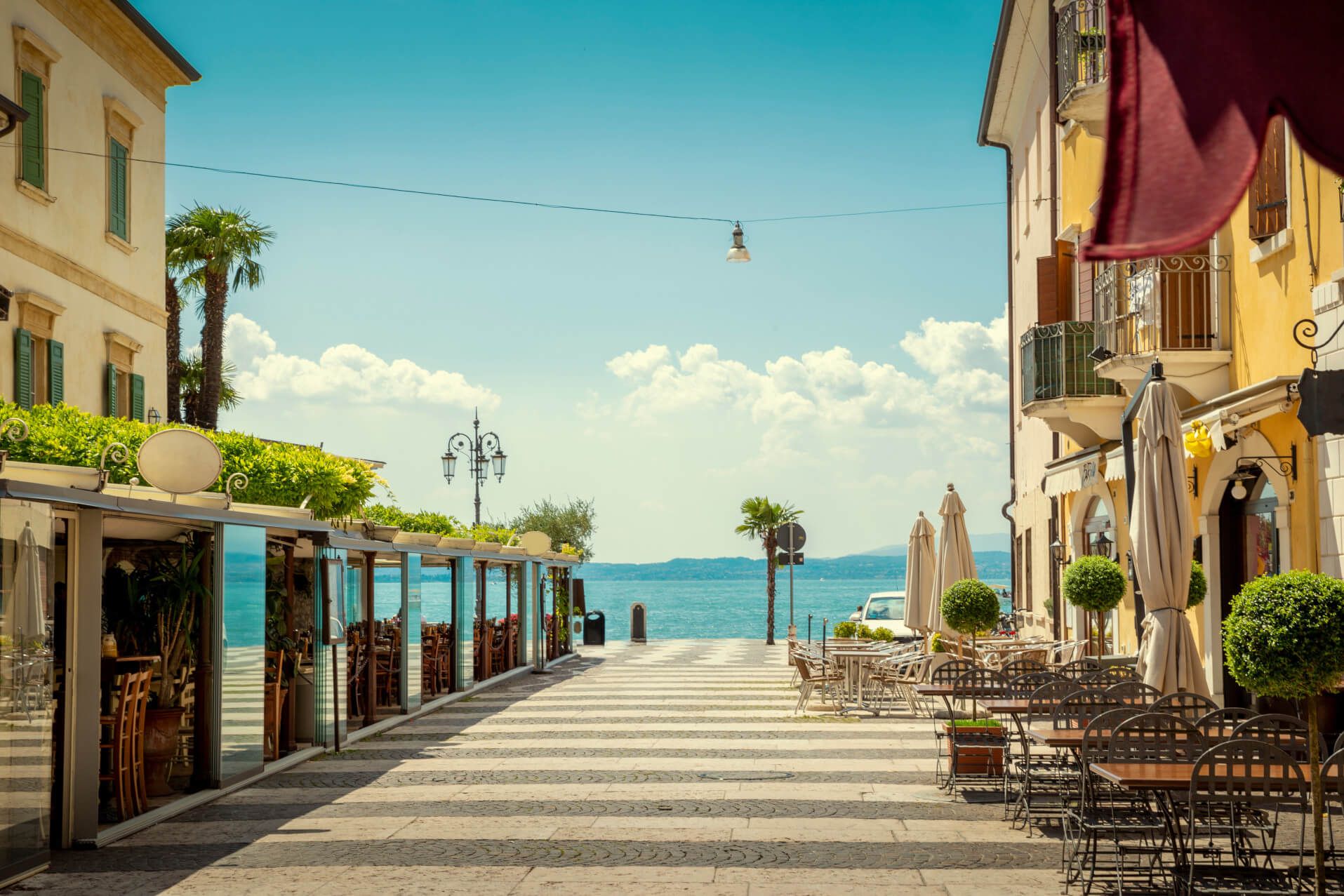 Eine malerische Uferpromenade mit Restaurants und Blick auf das Wasser unter einem blauen Himmel.